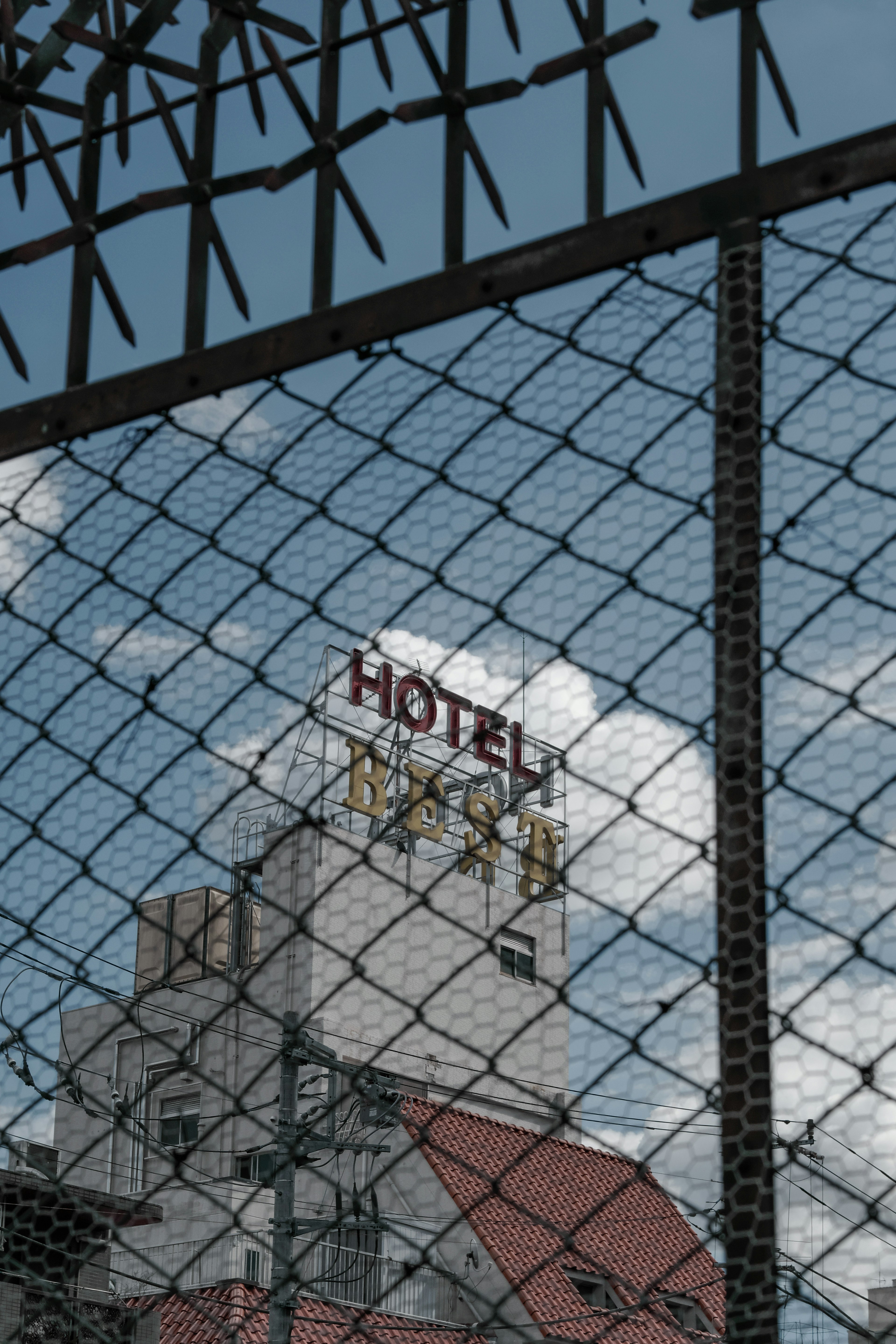 Hotel sign visible through a fence with blue sky