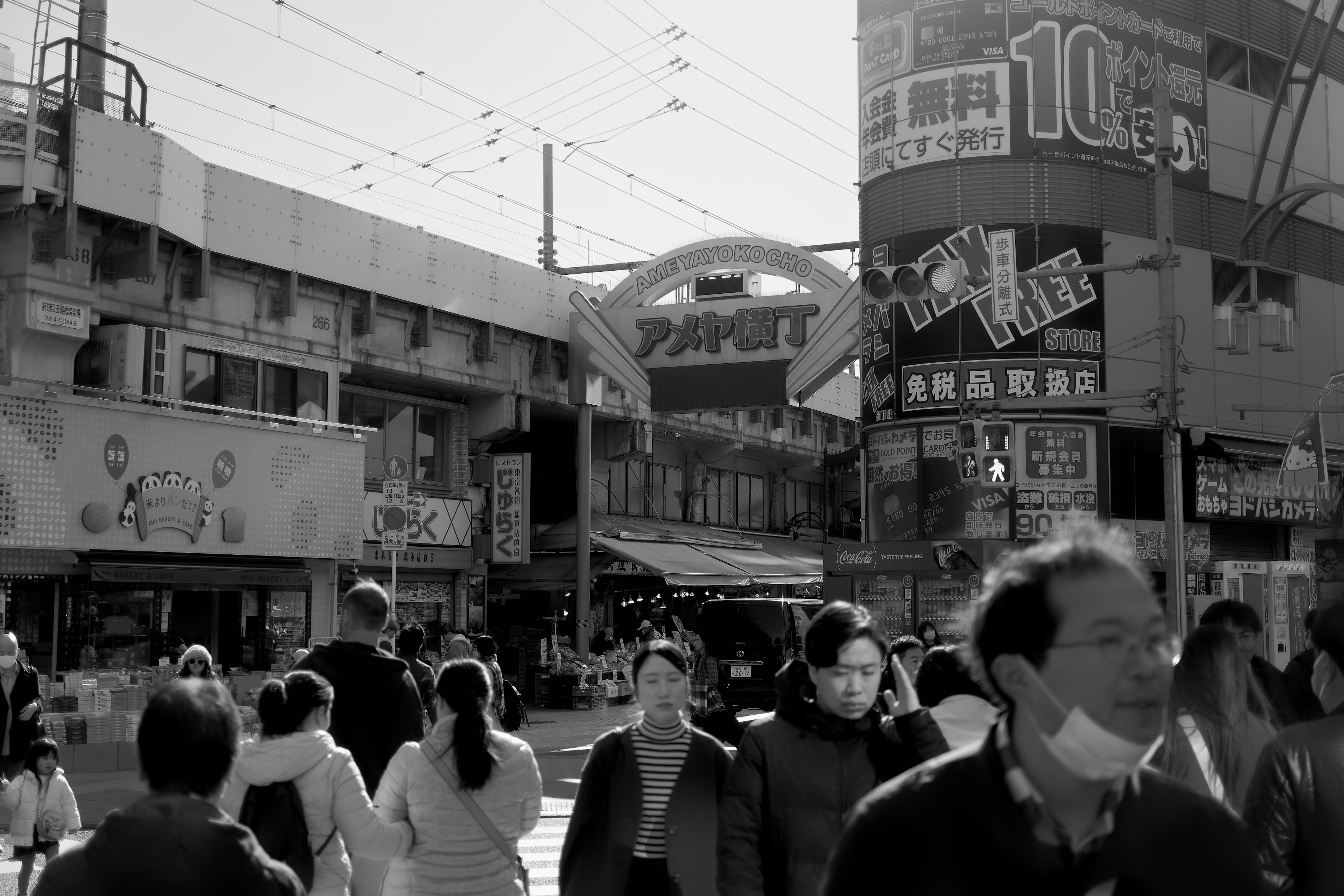 白黒の街並みで多くの人々が行き交う賑やかな交差点