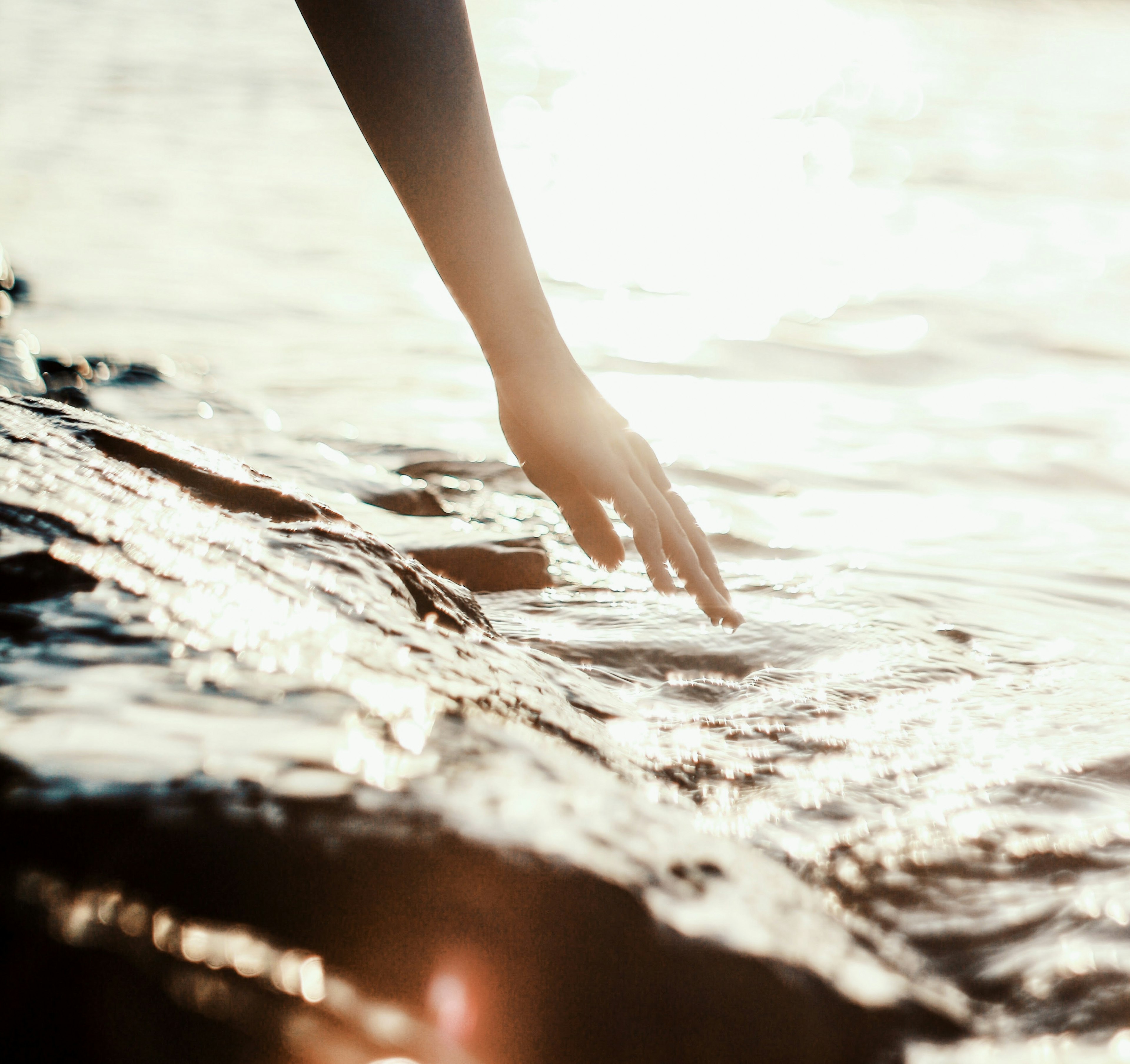 Gros plan d'une main touchant l'eau au bord