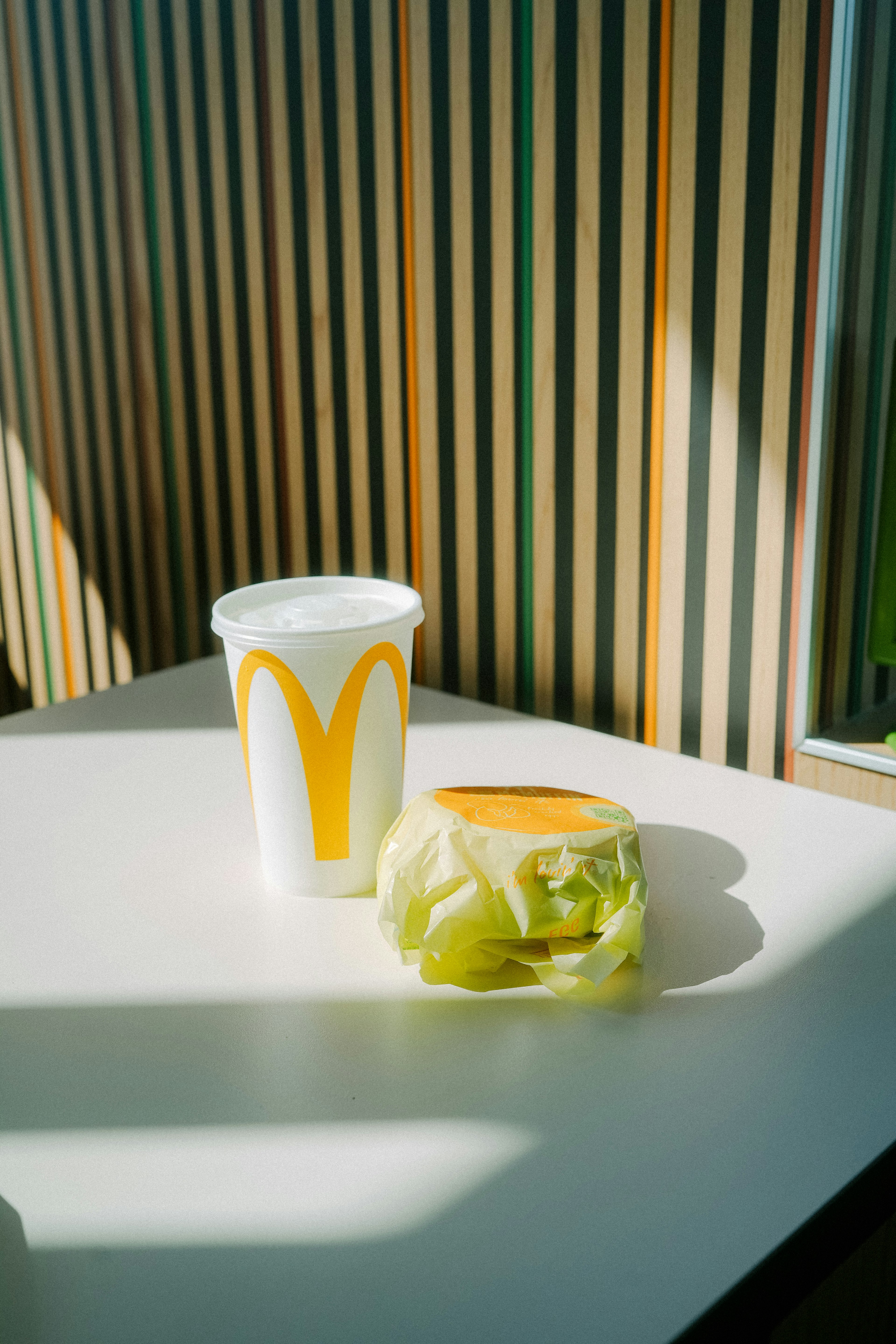 Un vaso de McDonald's y un sándwich de lechuga sobre una mesa blanca