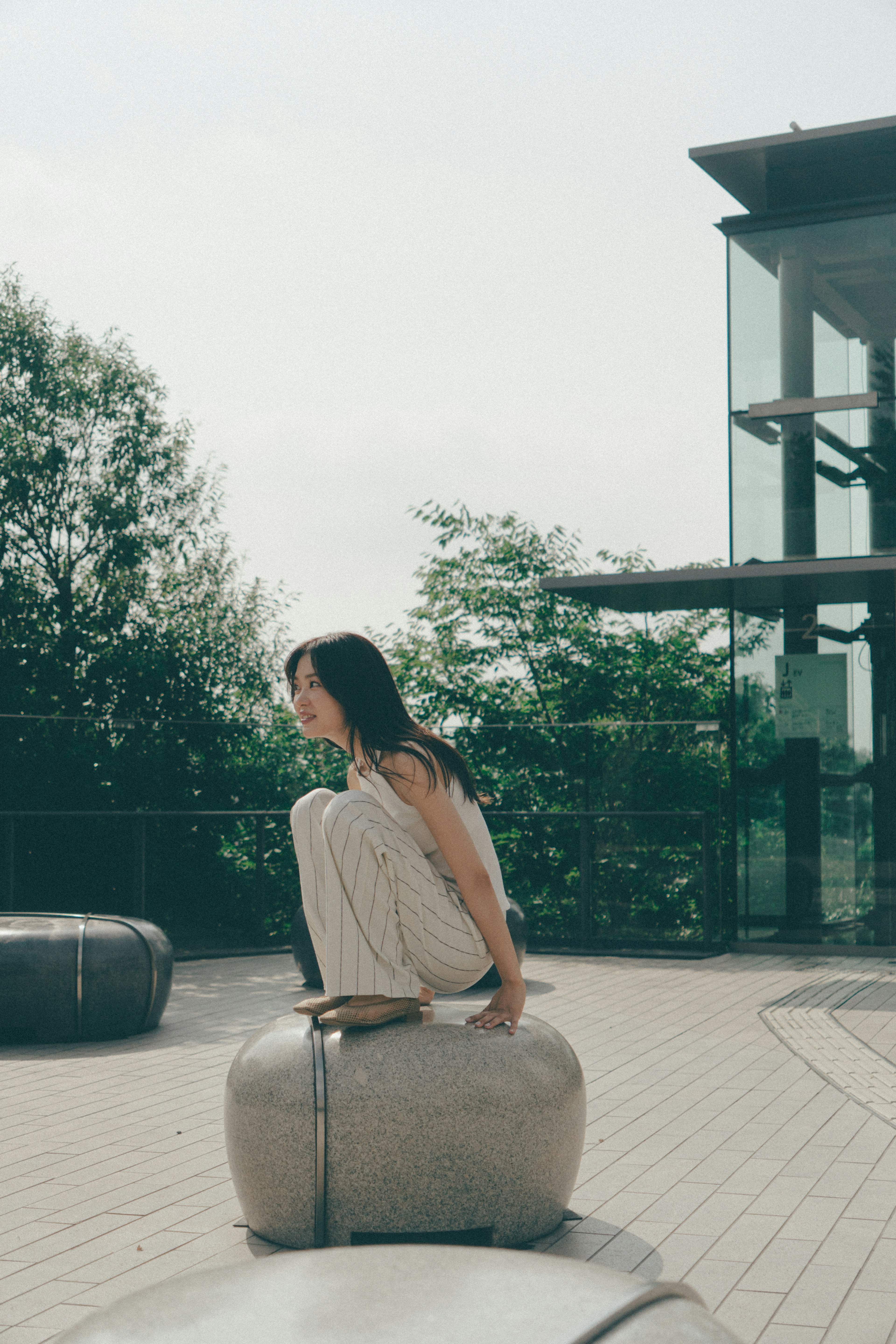 A woman sitting on a stone in an outdoor park setting