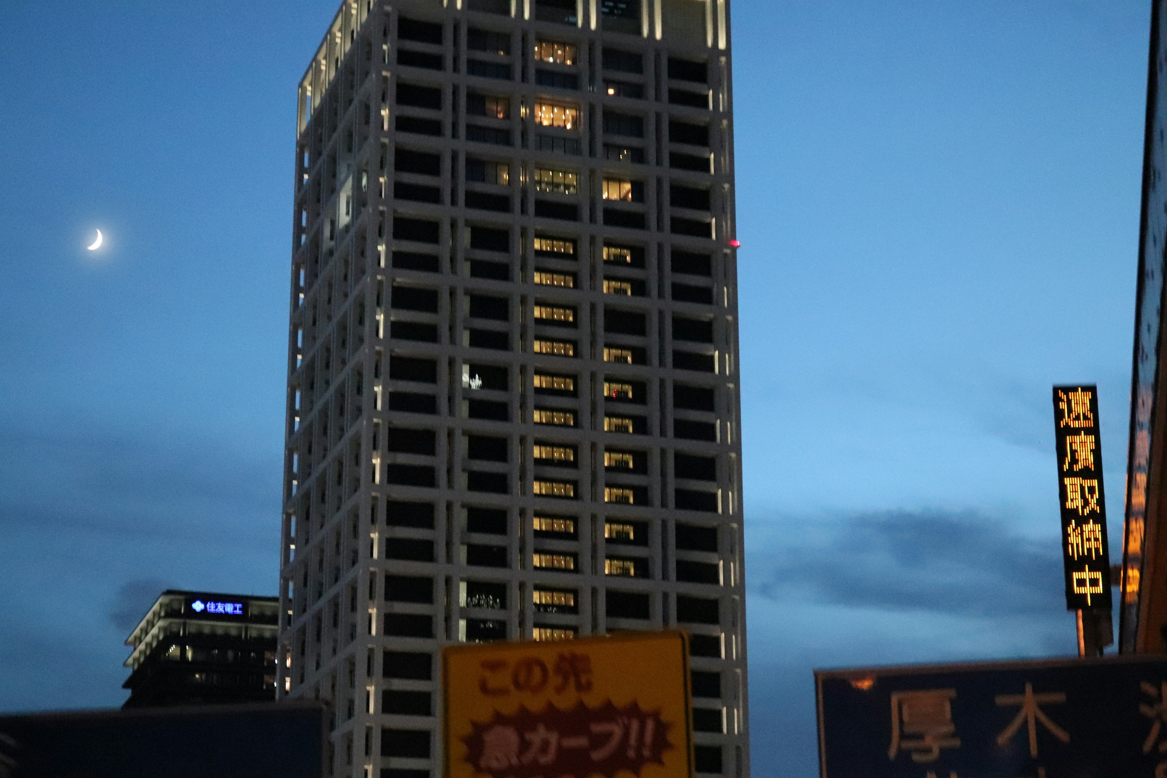 夜の青空の下に立つ高層ビルと明るい看板