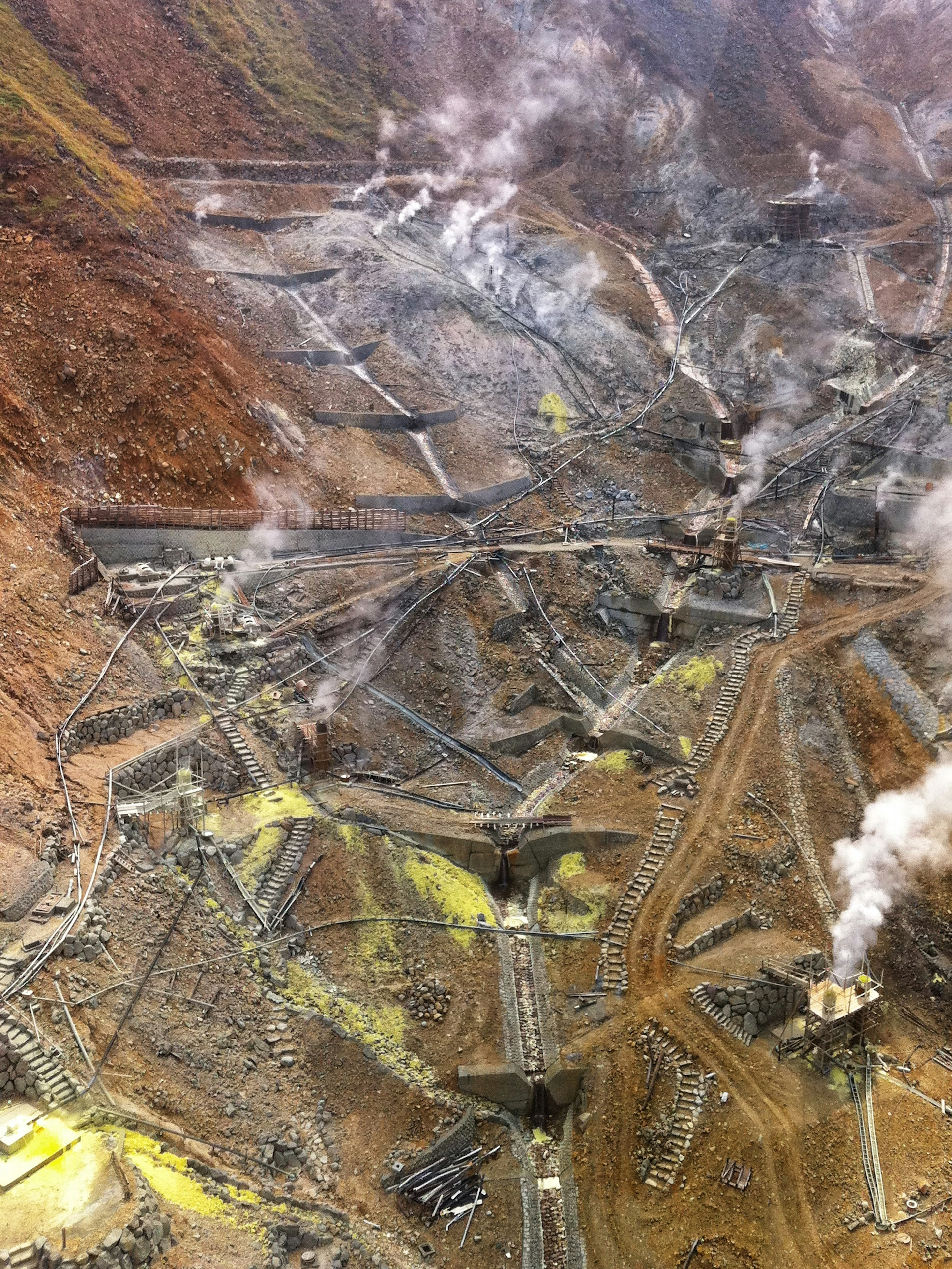 Vista aerea di un sito minerario con strutture che emettono fumi e minerali verdastri