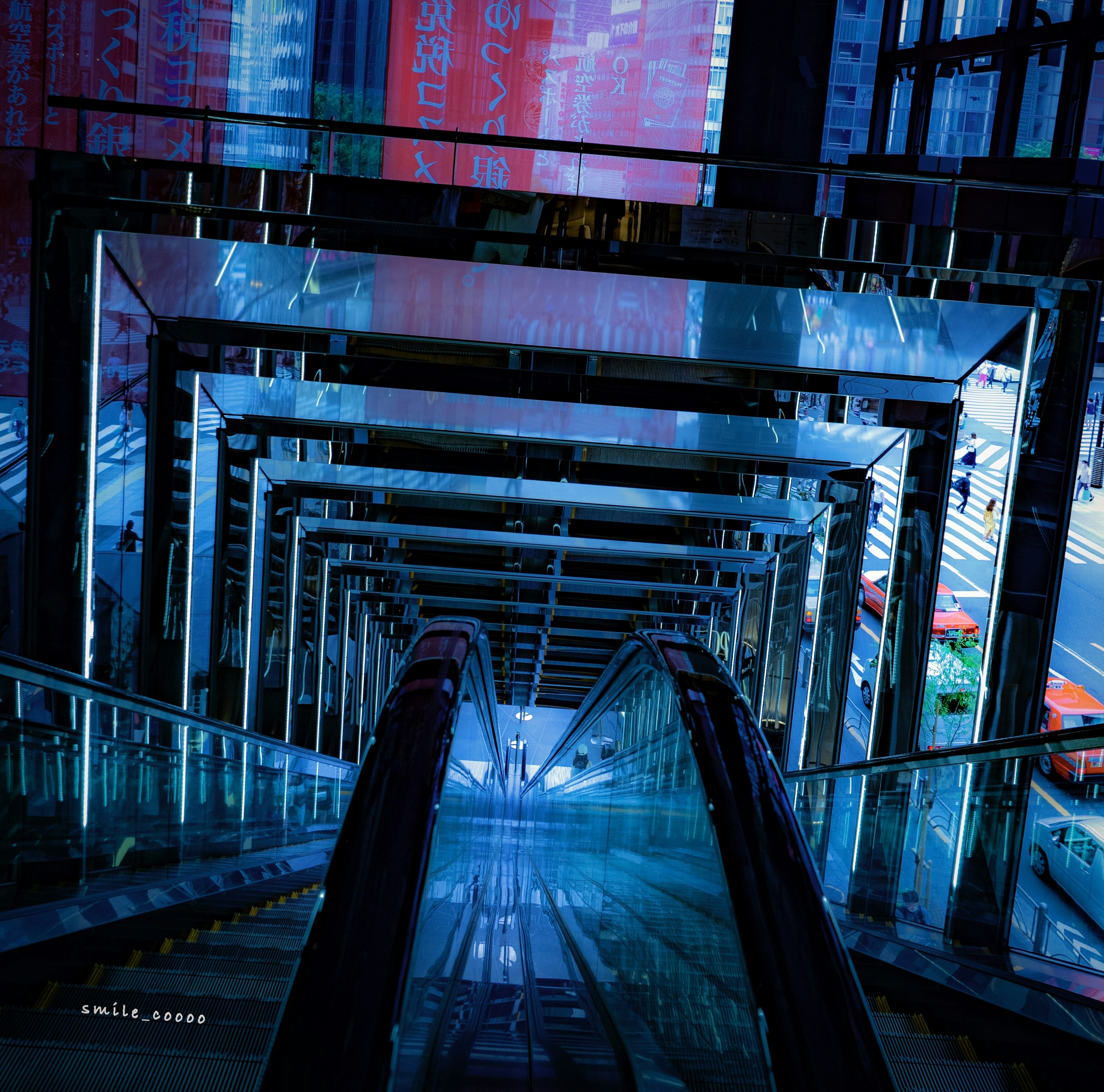 View from a futuristic escalator showcasing transparent glass structure and blue lighting