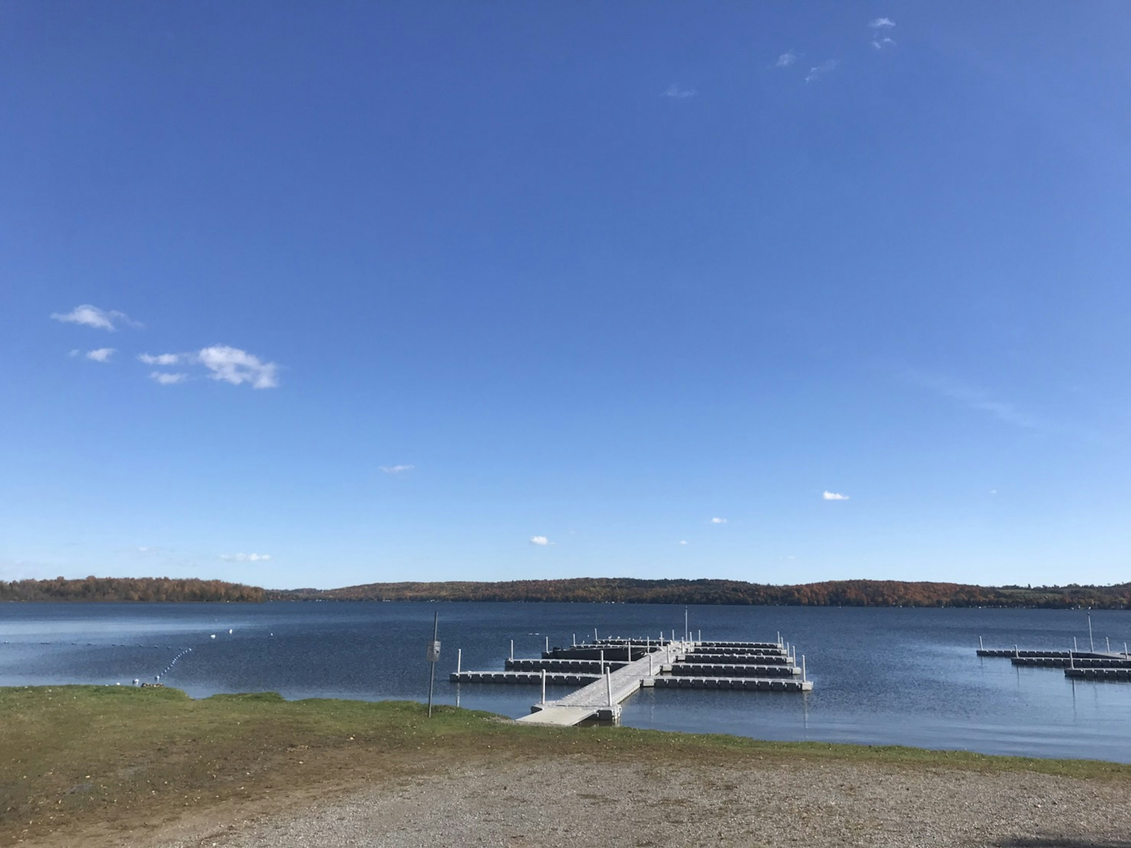 Scenic view of a calm lake under a blue sky featuring a dock and boat slips