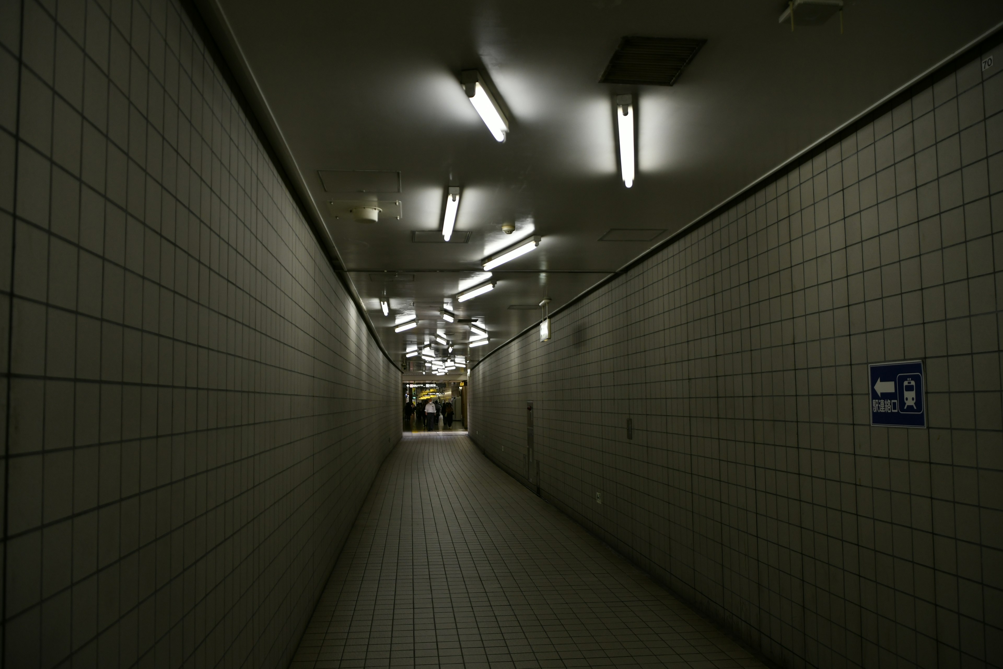 Long tiled corridor illuminated by fluorescent lights