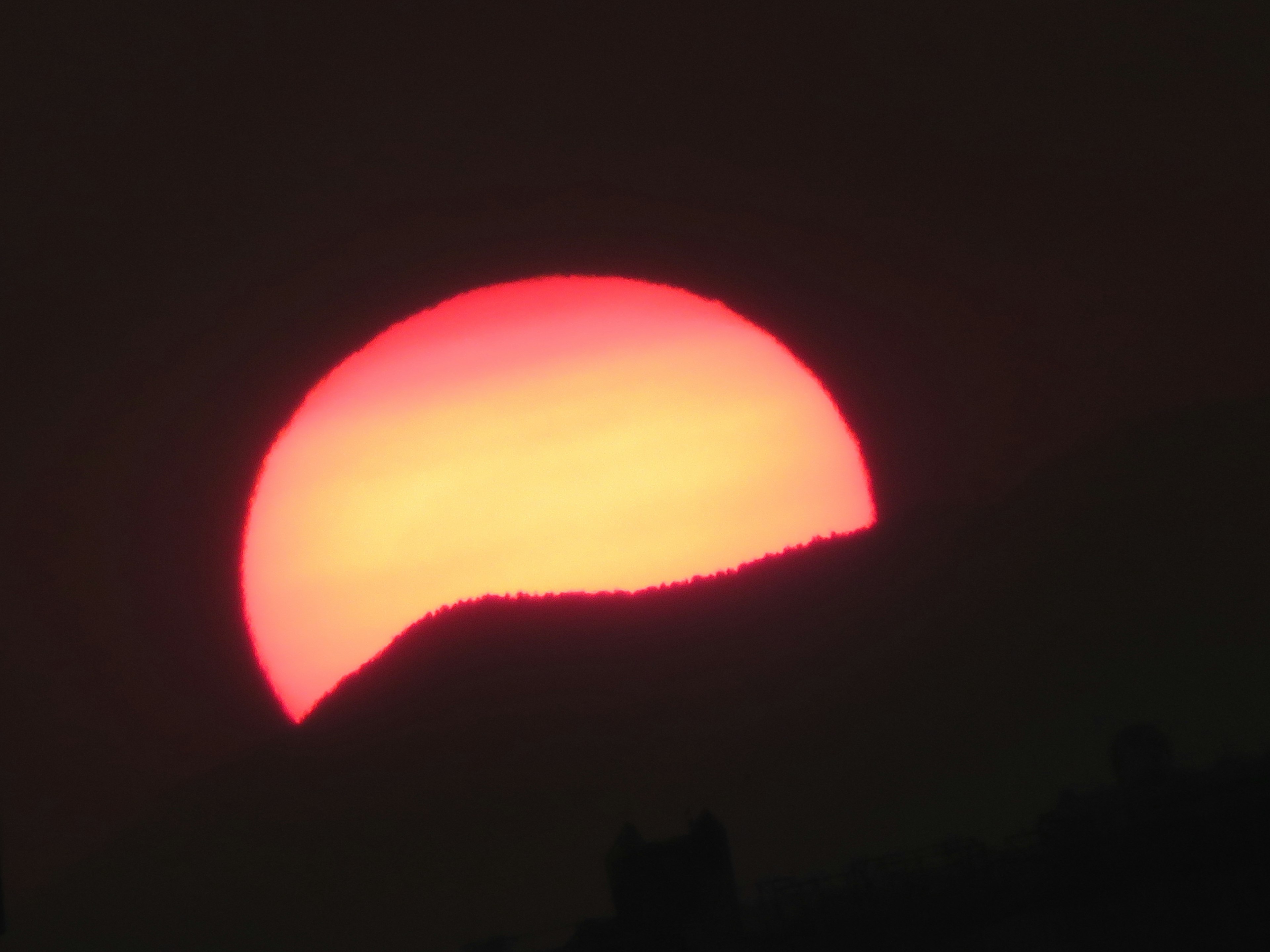 Orange sun setting behind a mountain