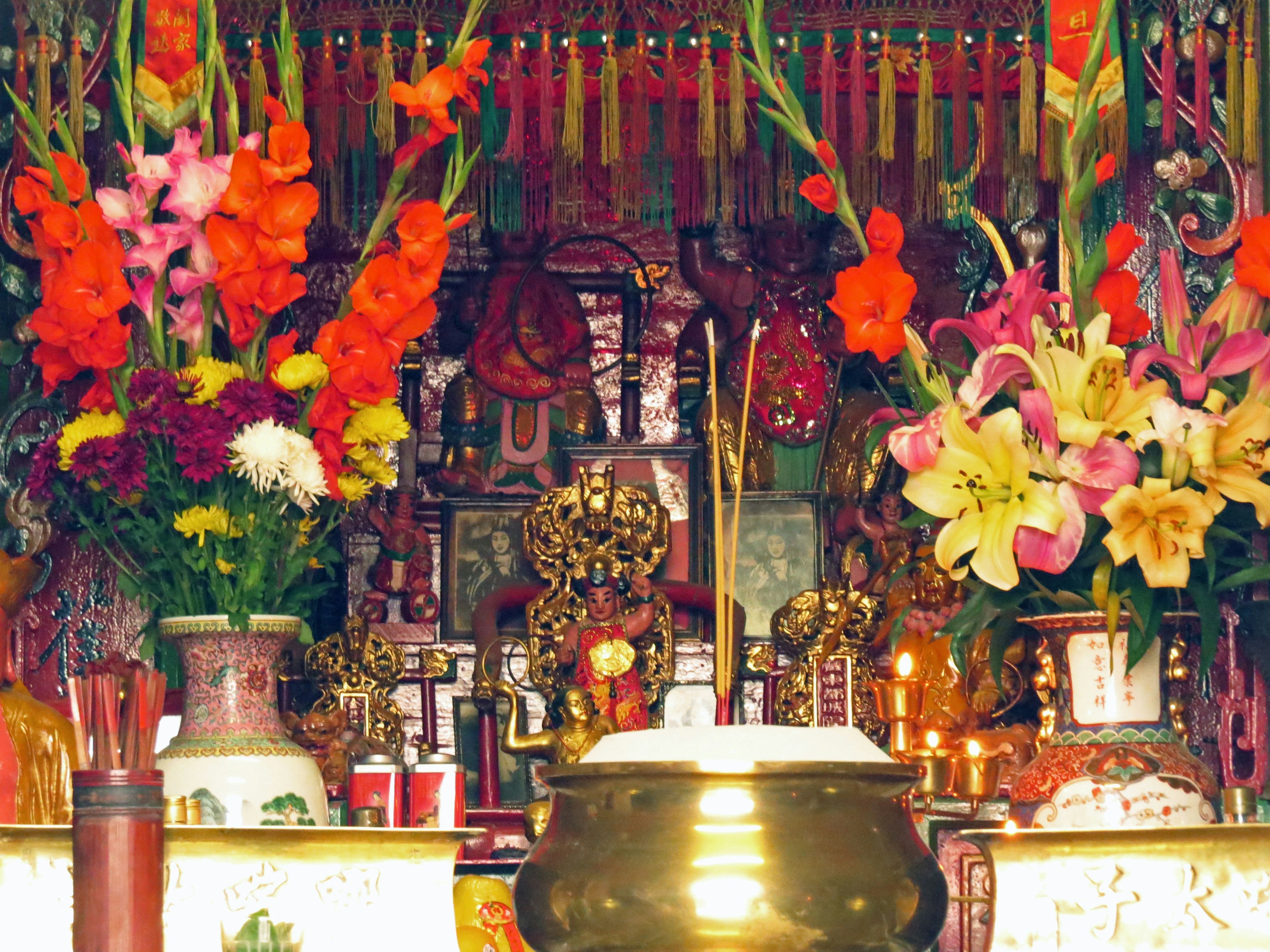 Colorful flowers adorning an altar with a golden incense burner in a religious setting