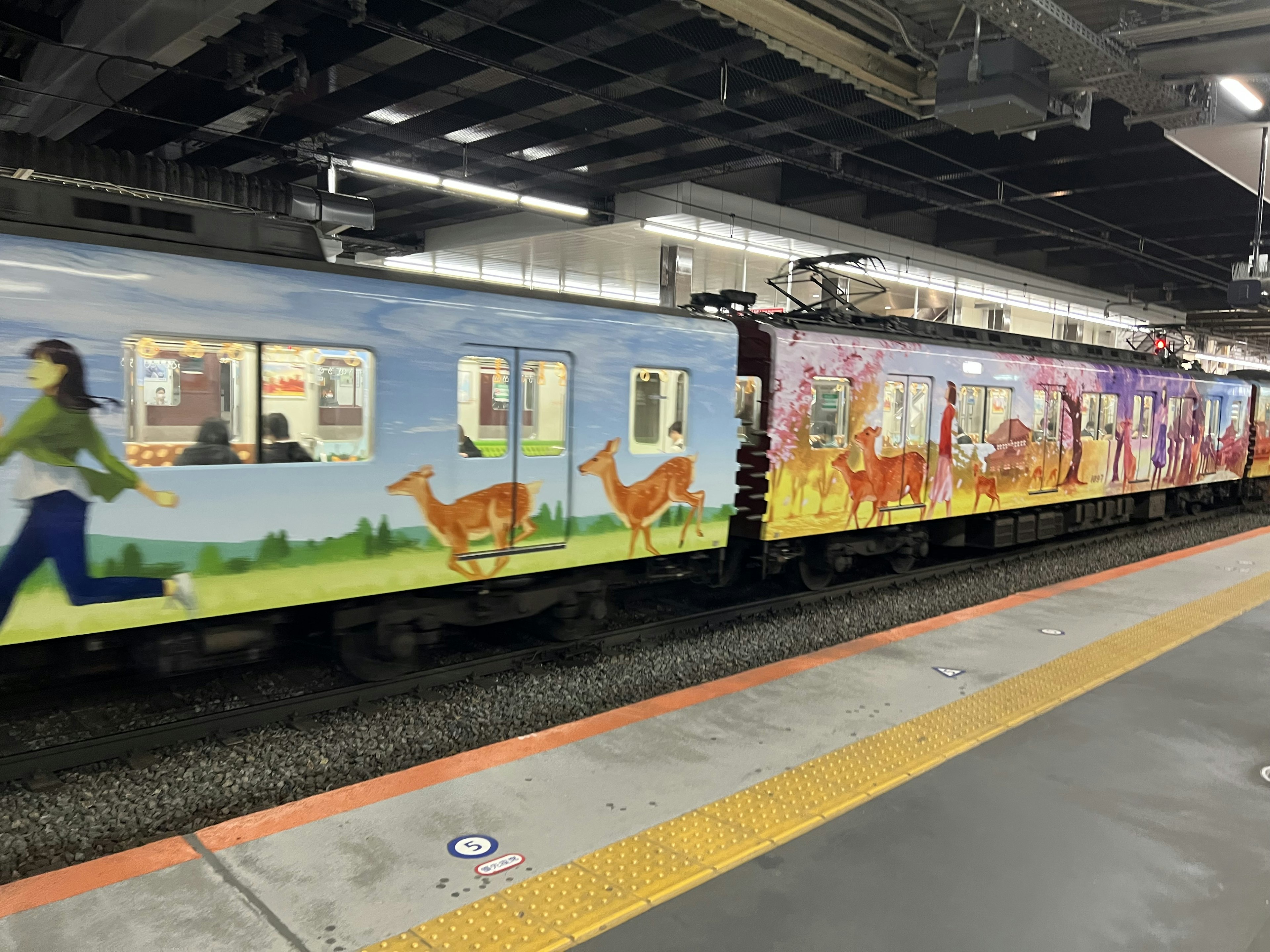 A colorful train with artistic designs is stopped at a station