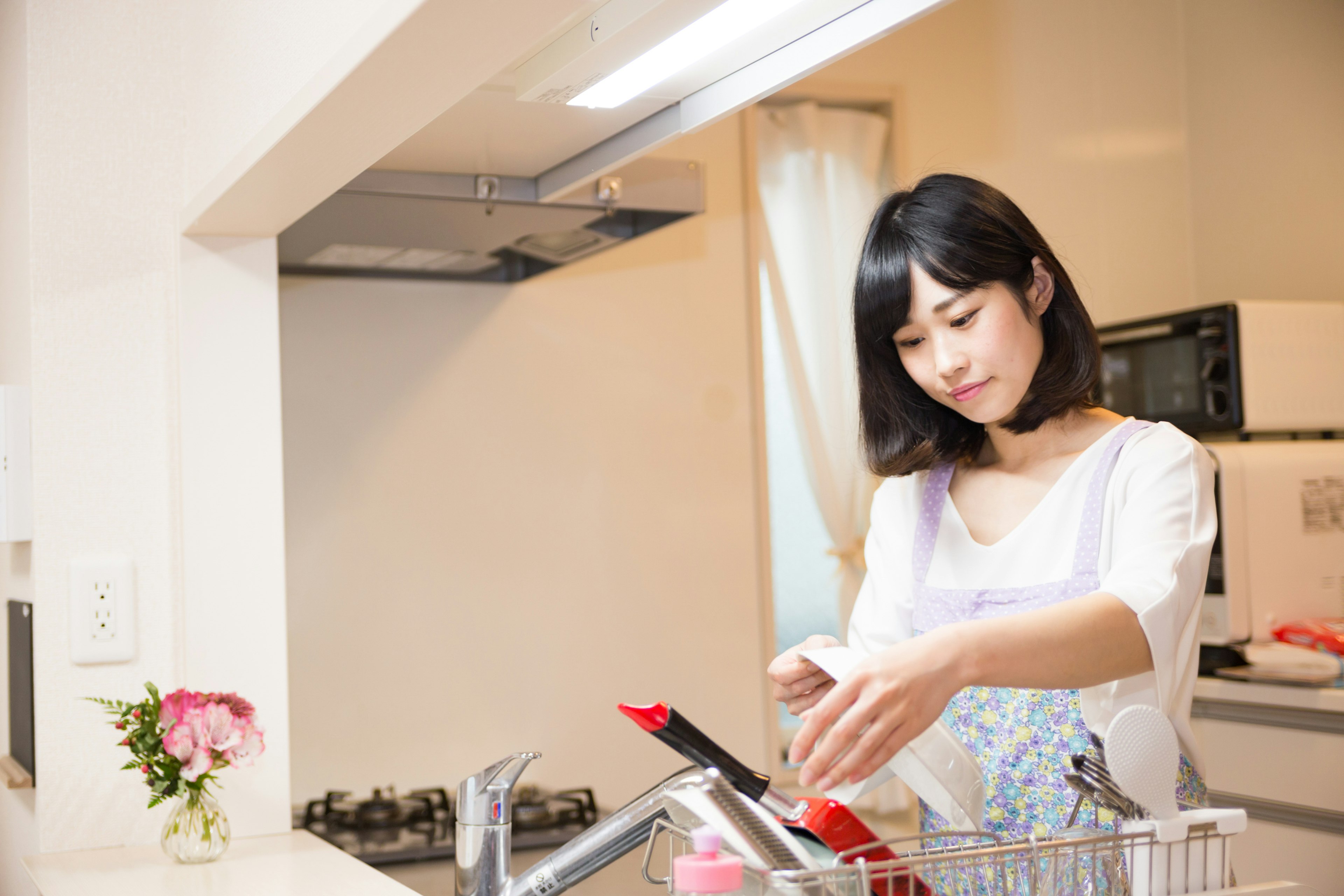 Wanita mencuci piring di dapur modern