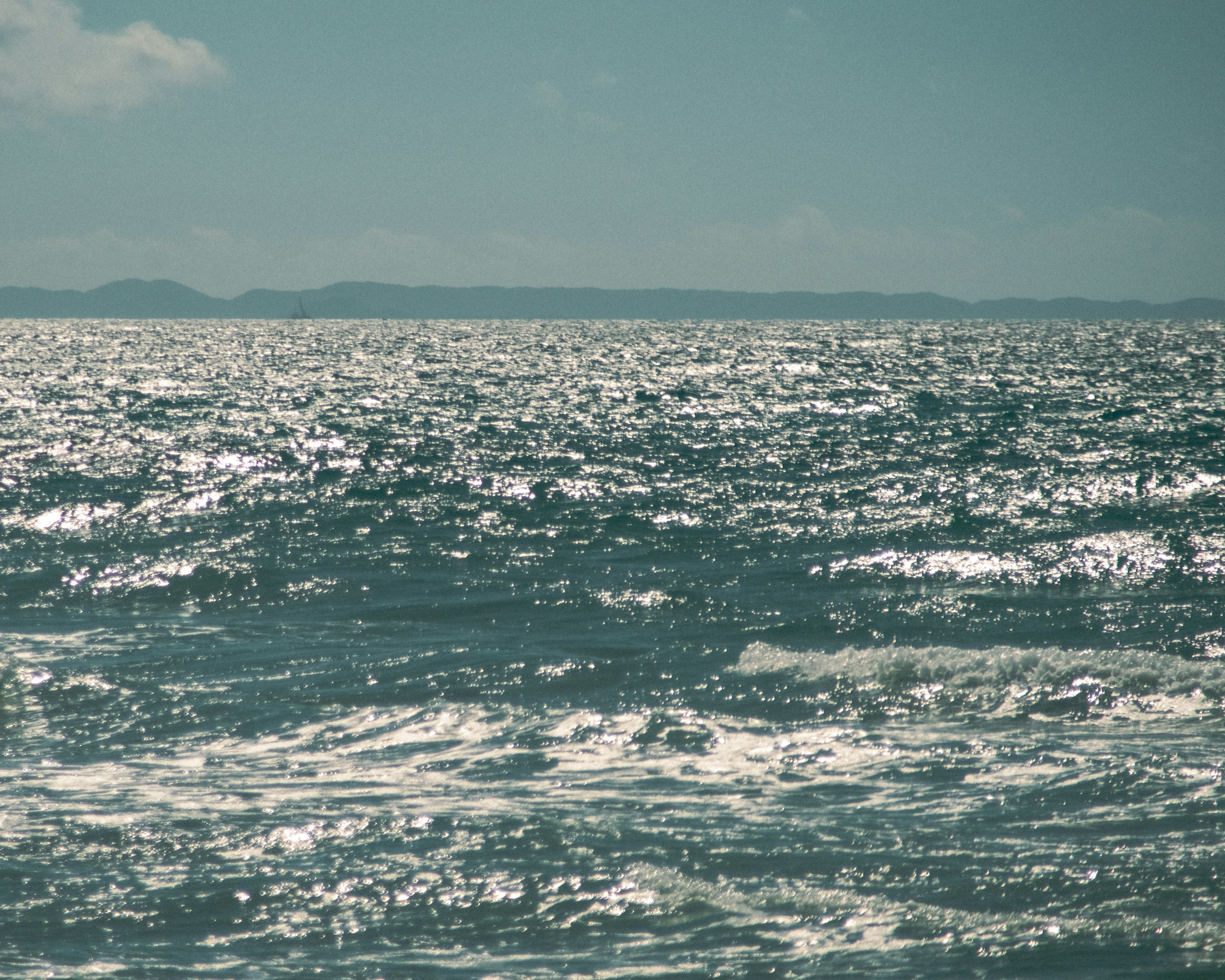 Vue de la mer calme avec des vagues scintillantes et des îles lointaines