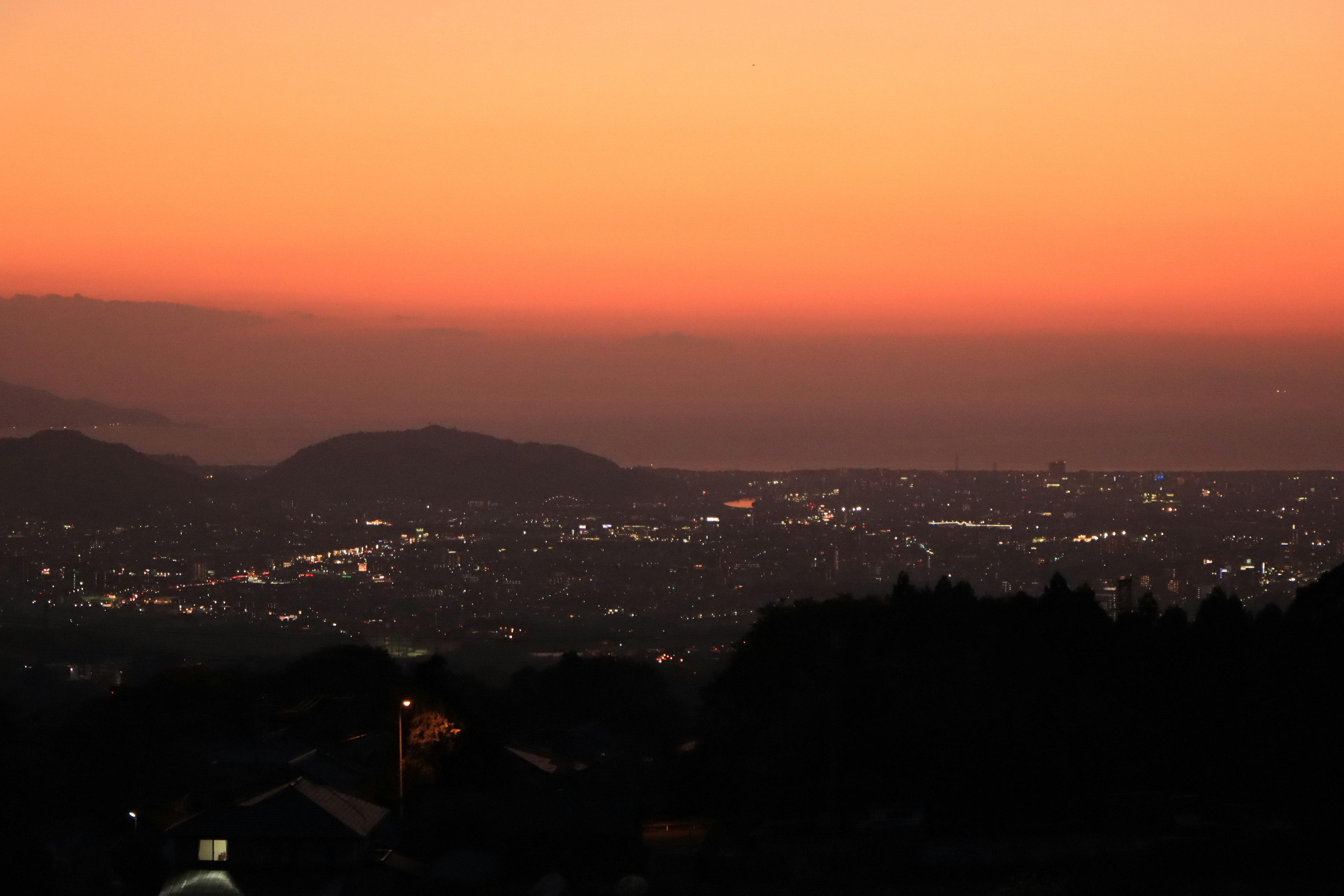 Cielo de atardecer con luces de la ciudad y montañas al fondo