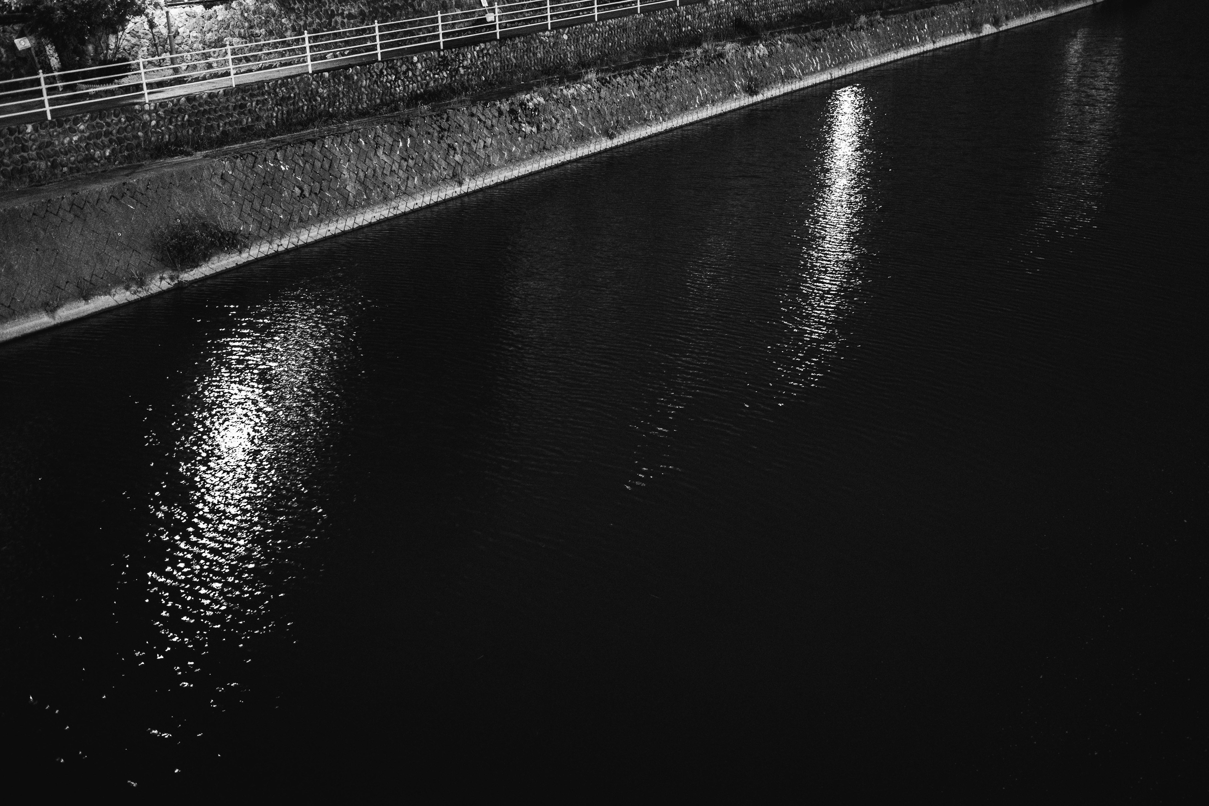 Reflections of lights on a dark river surface at night