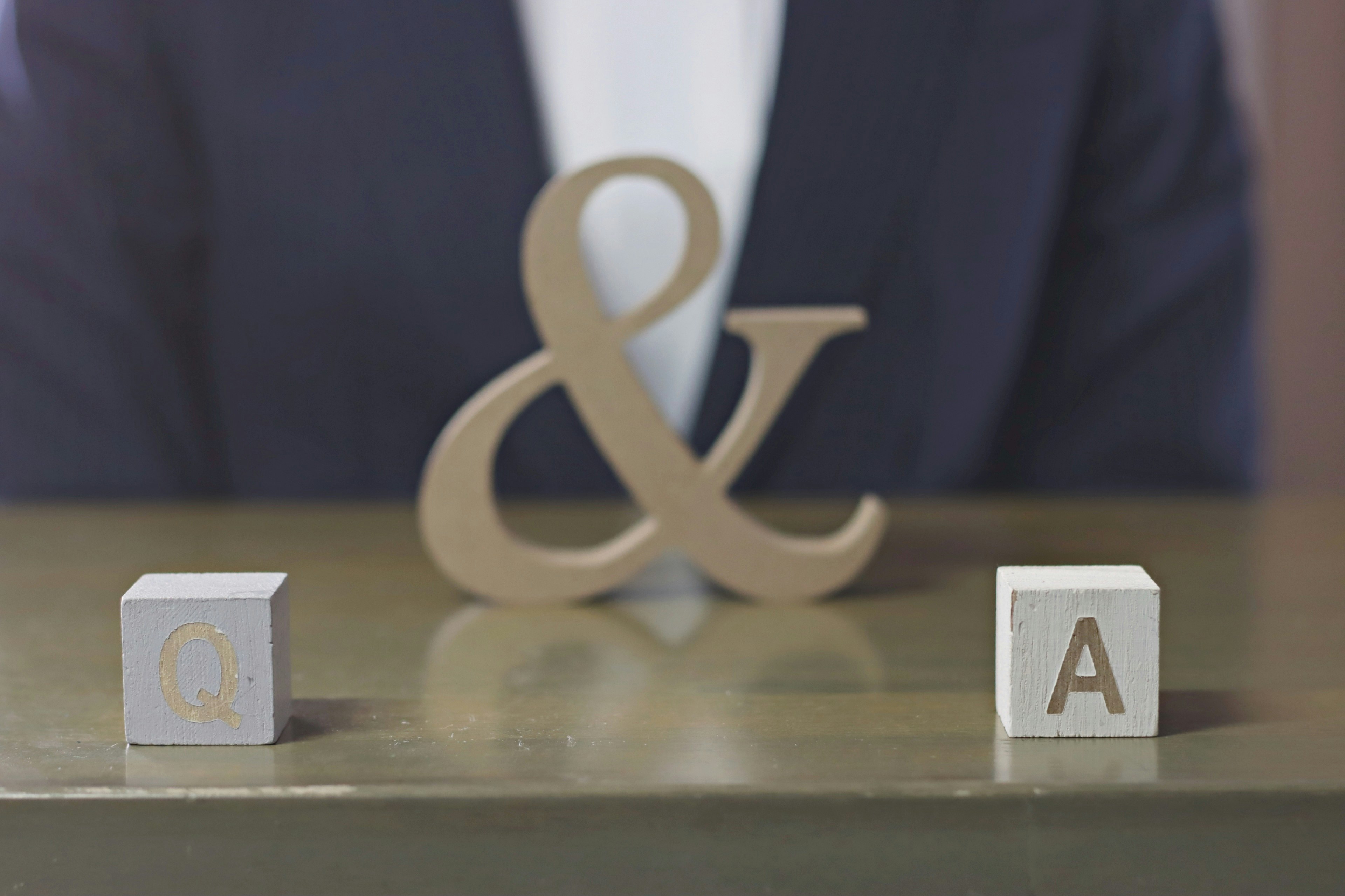 Un gran símbolo de ampersand sobre una mesa con bloques de madera que muestran las letras L y A