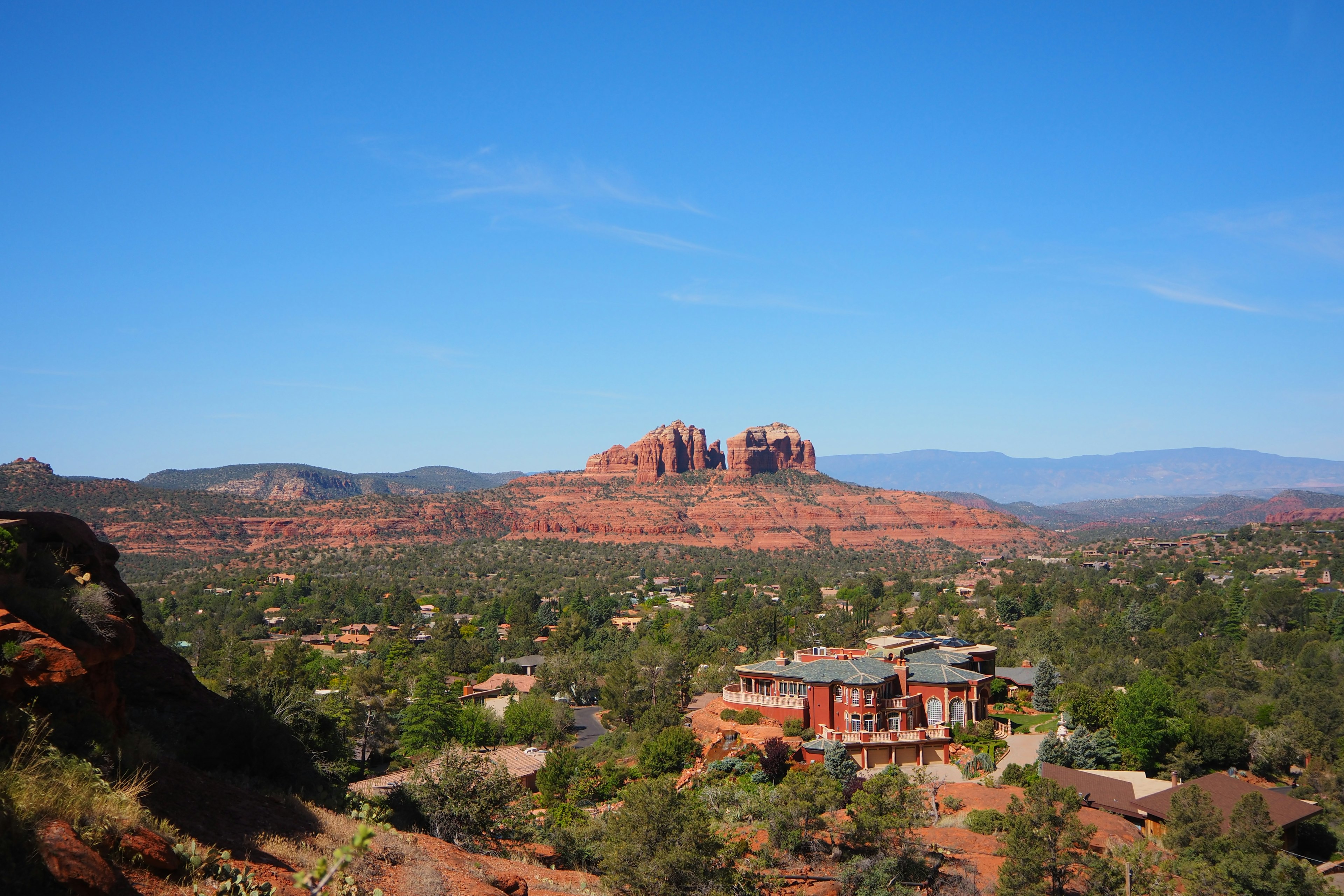 Panoramablick auf die roten Felsen von Sedona und das üppige Grün unter einem klaren blauen Himmel