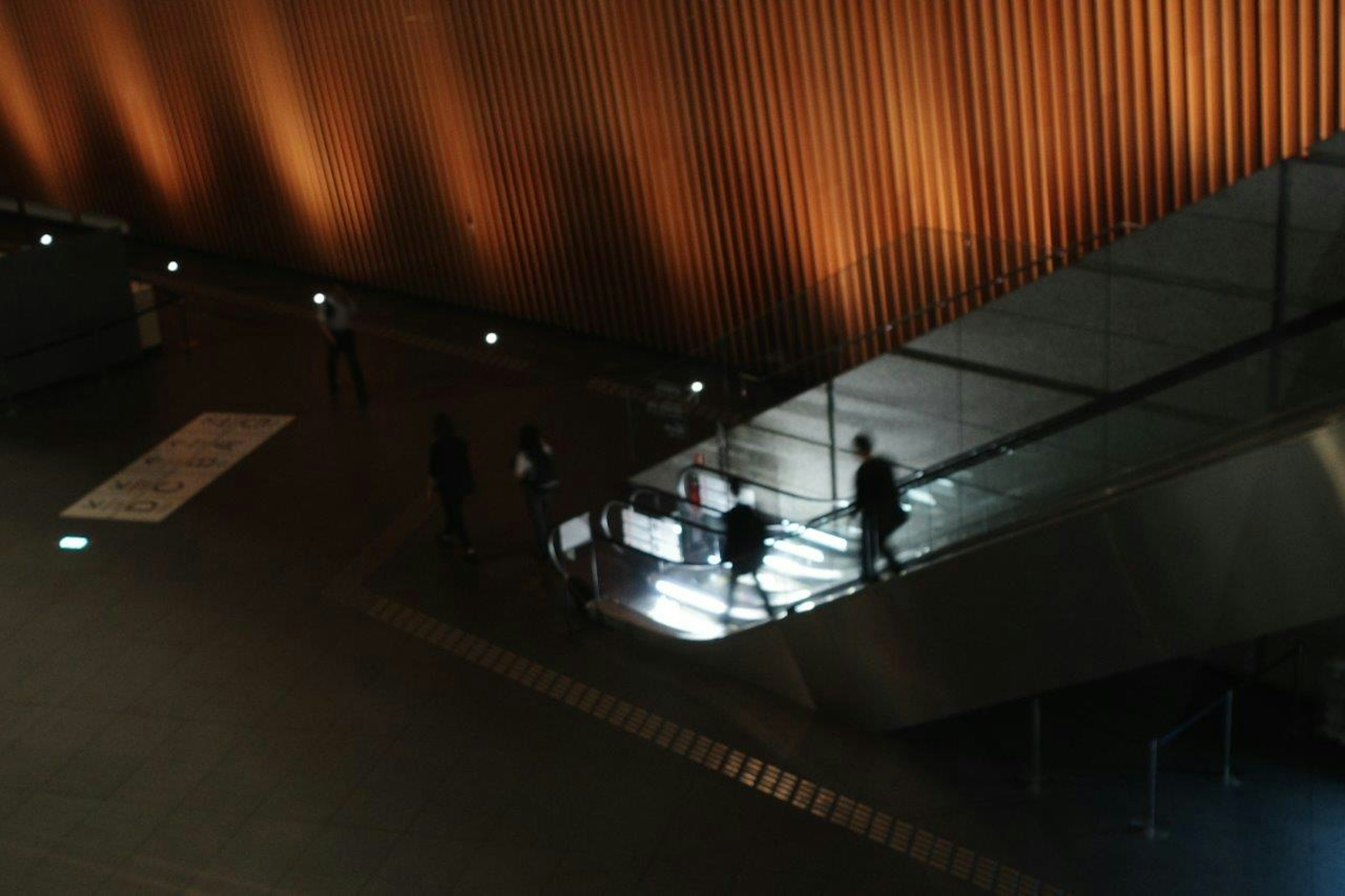 Menschen, die in einer schwach beleuchteten Umgebung mit einer orangefarbenen Wand Treppen hinuntergehen