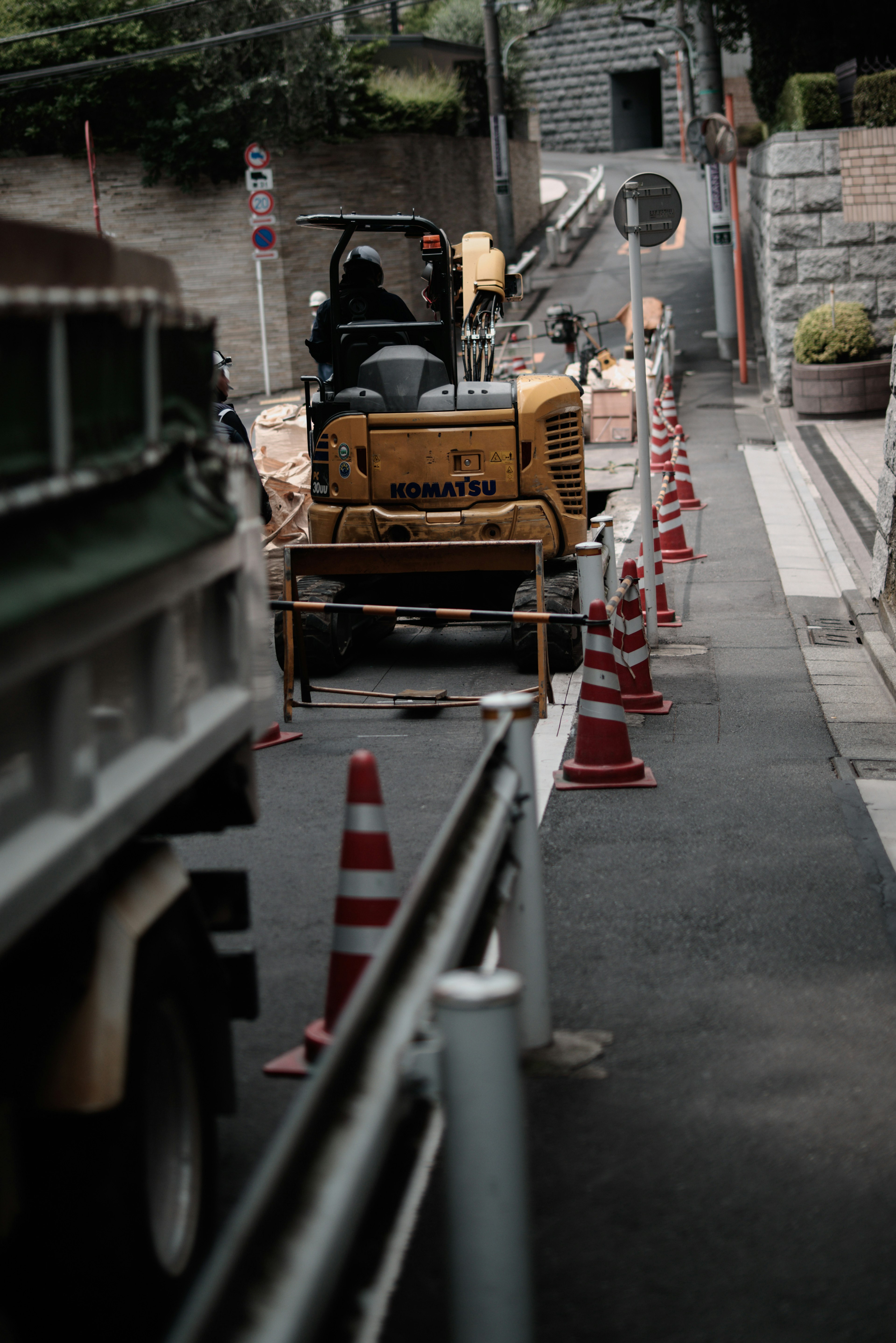 Sitio de construcción con maquinaria y conos de tráfico a lo largo de la calle