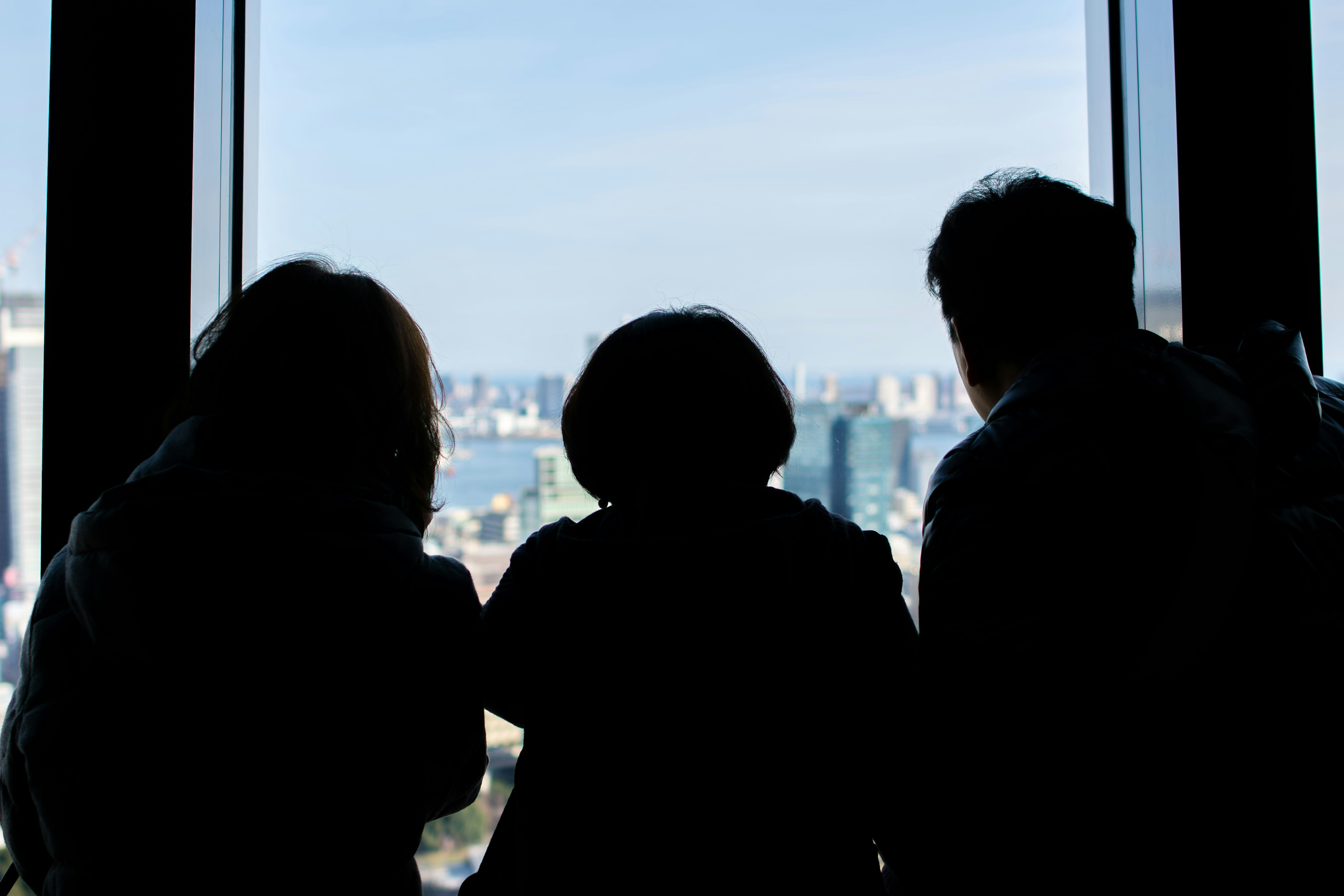 Silhouette di persone che guardano fuori da una finestra cielo blu e paesaggio urbano