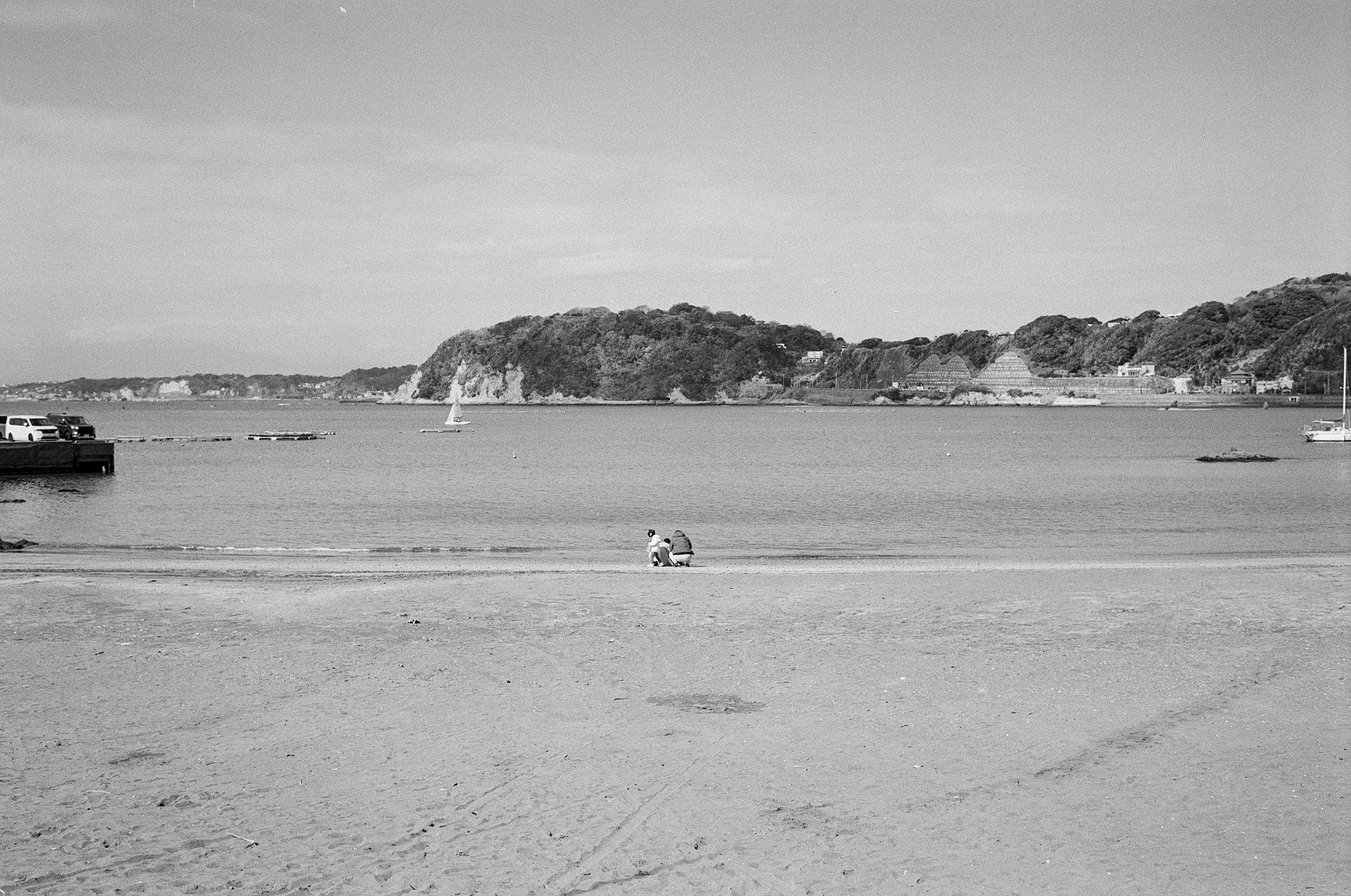 Escena costera en blanco y negro con barcos y un yate en aguas tranquilas