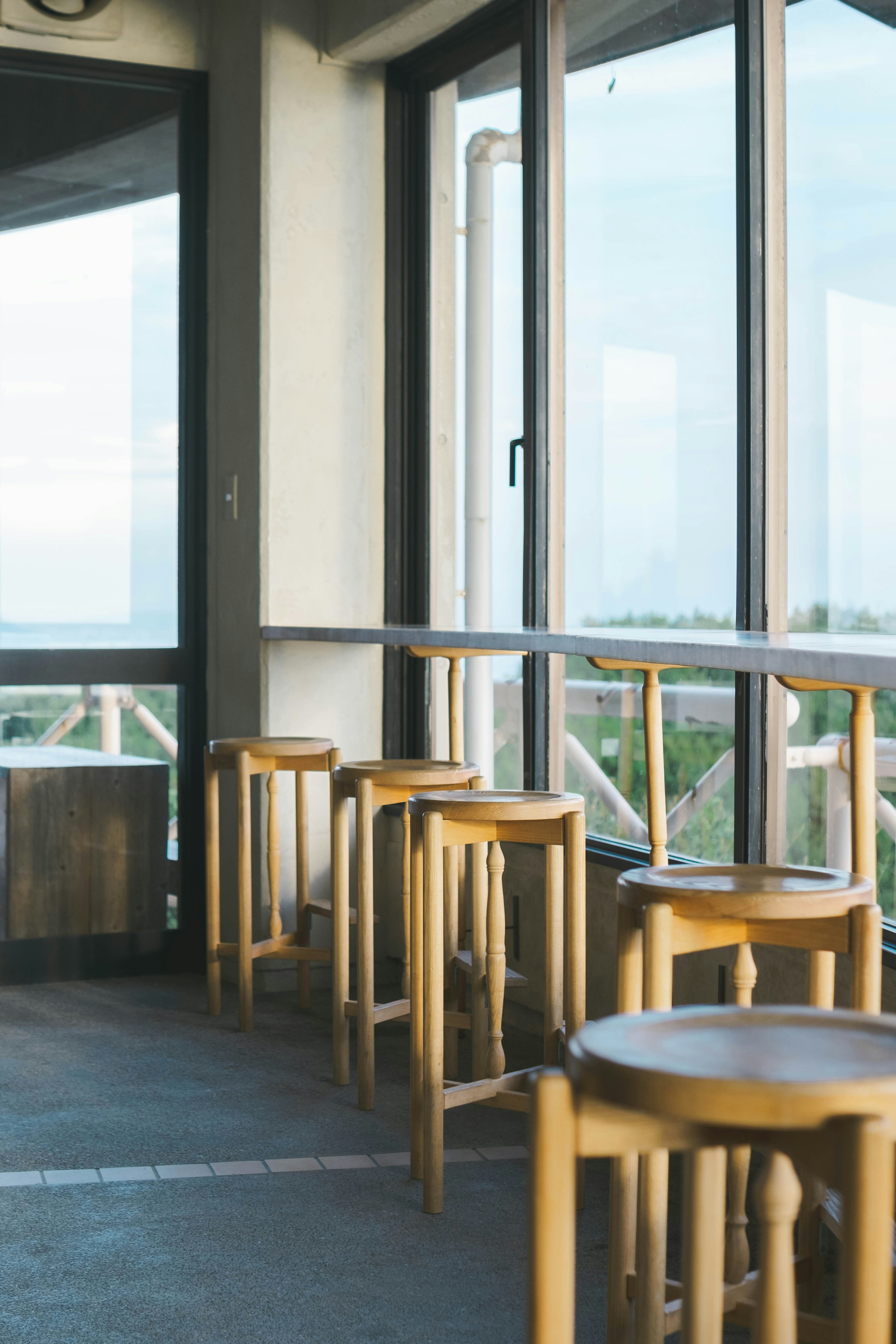 Intérieur d'un café avec des tabourets en bois disposés près de grandes fenêtres