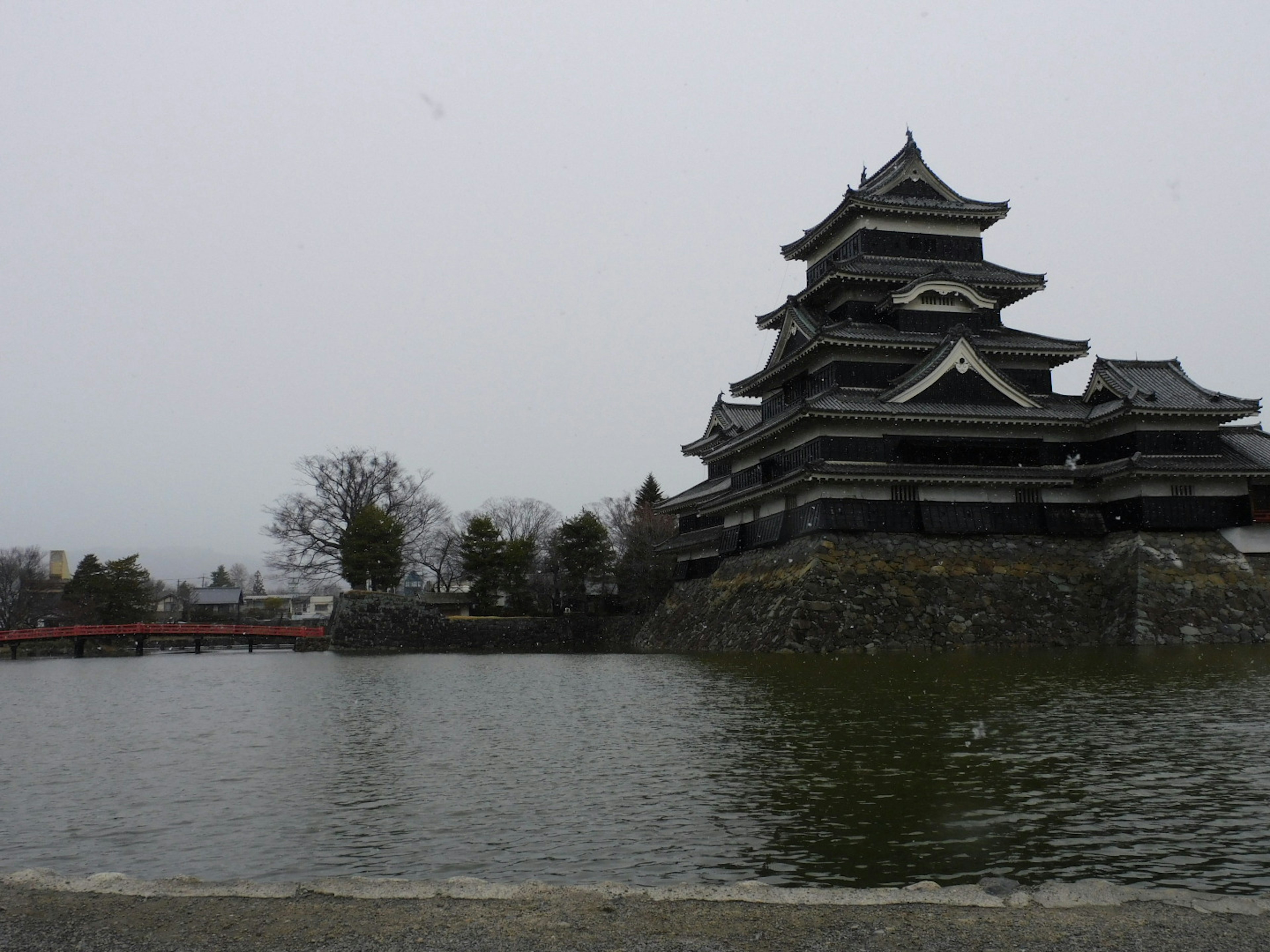 Castello di Matsumoto con tetto nero accanto a uno stagno tranquillo