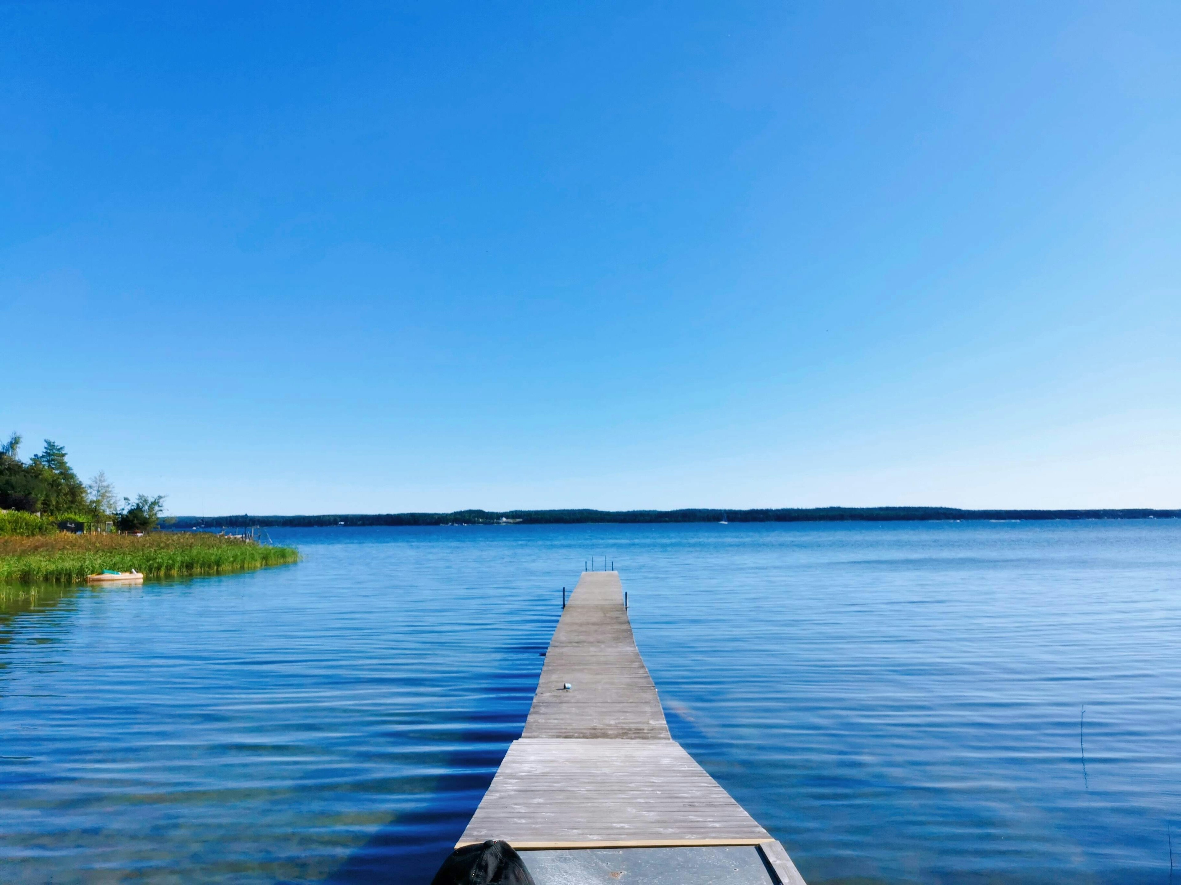 Lago tranquillo sotto un cielo blu con un molo in legno