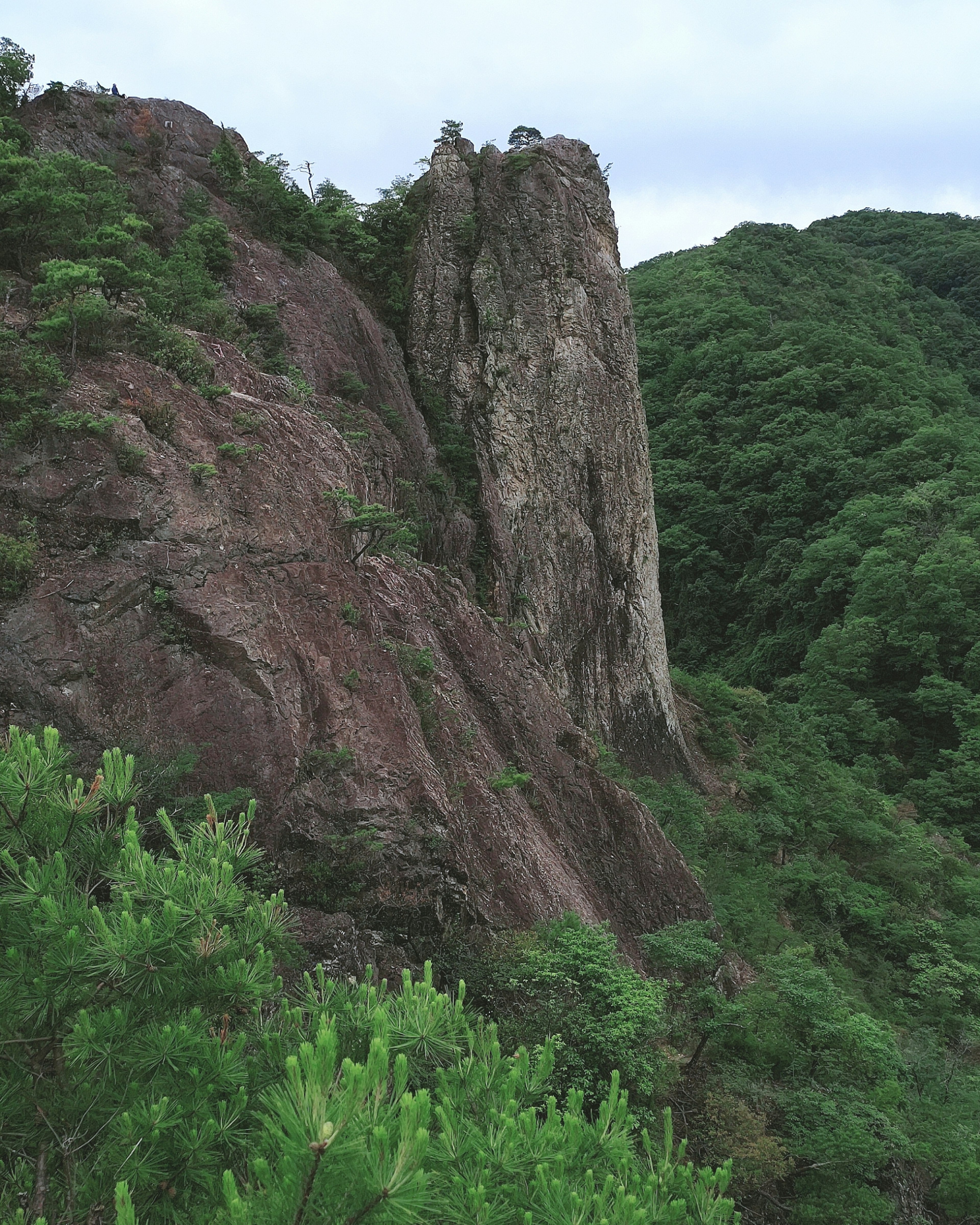 Tall rock pinnacle surrounded by green mountains