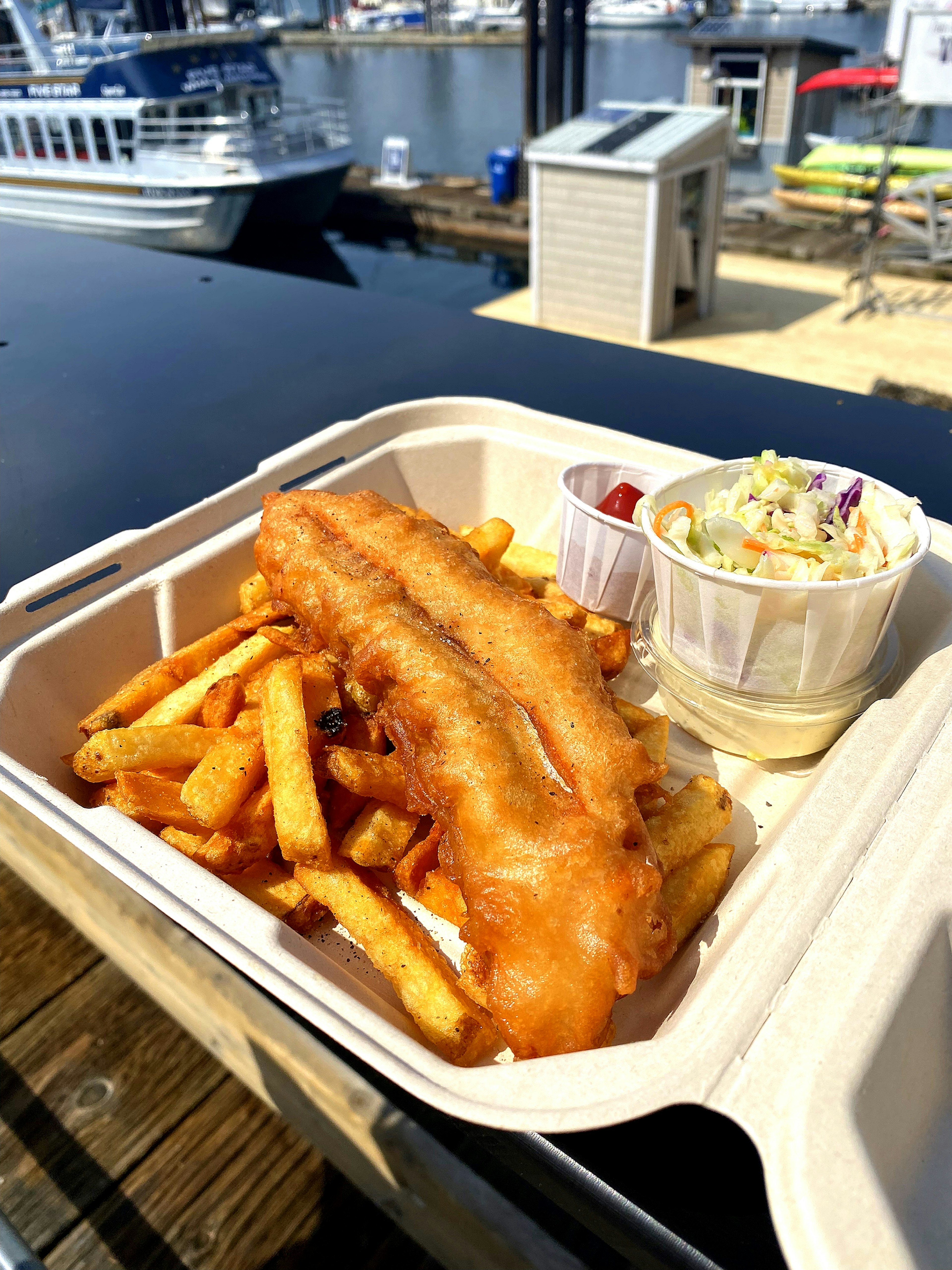 Takeout box with fried fish and fries served with coleslaw