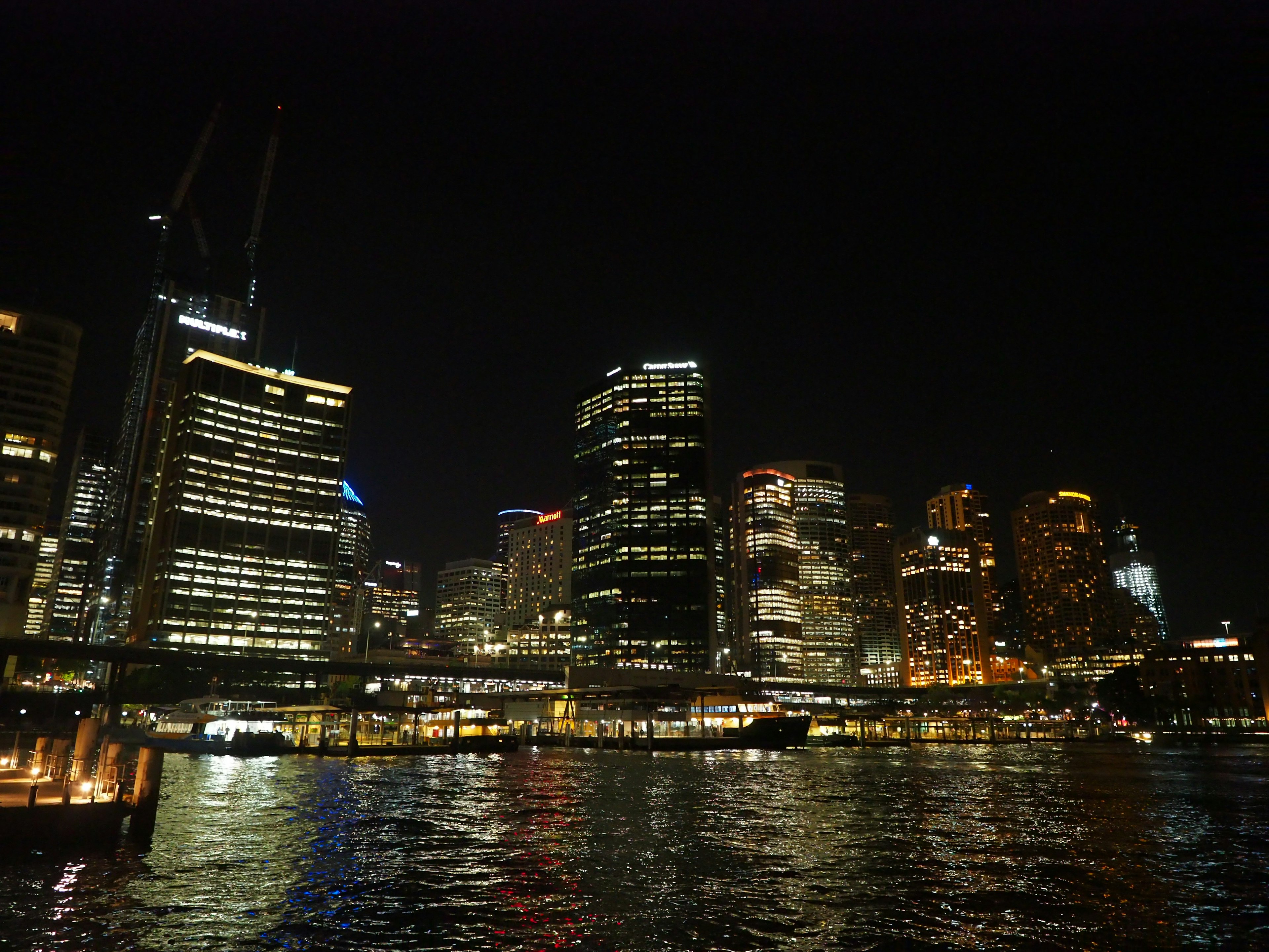 Pemandangan malam Sydney dengan gedung pencakar langit yang menyala di atas air