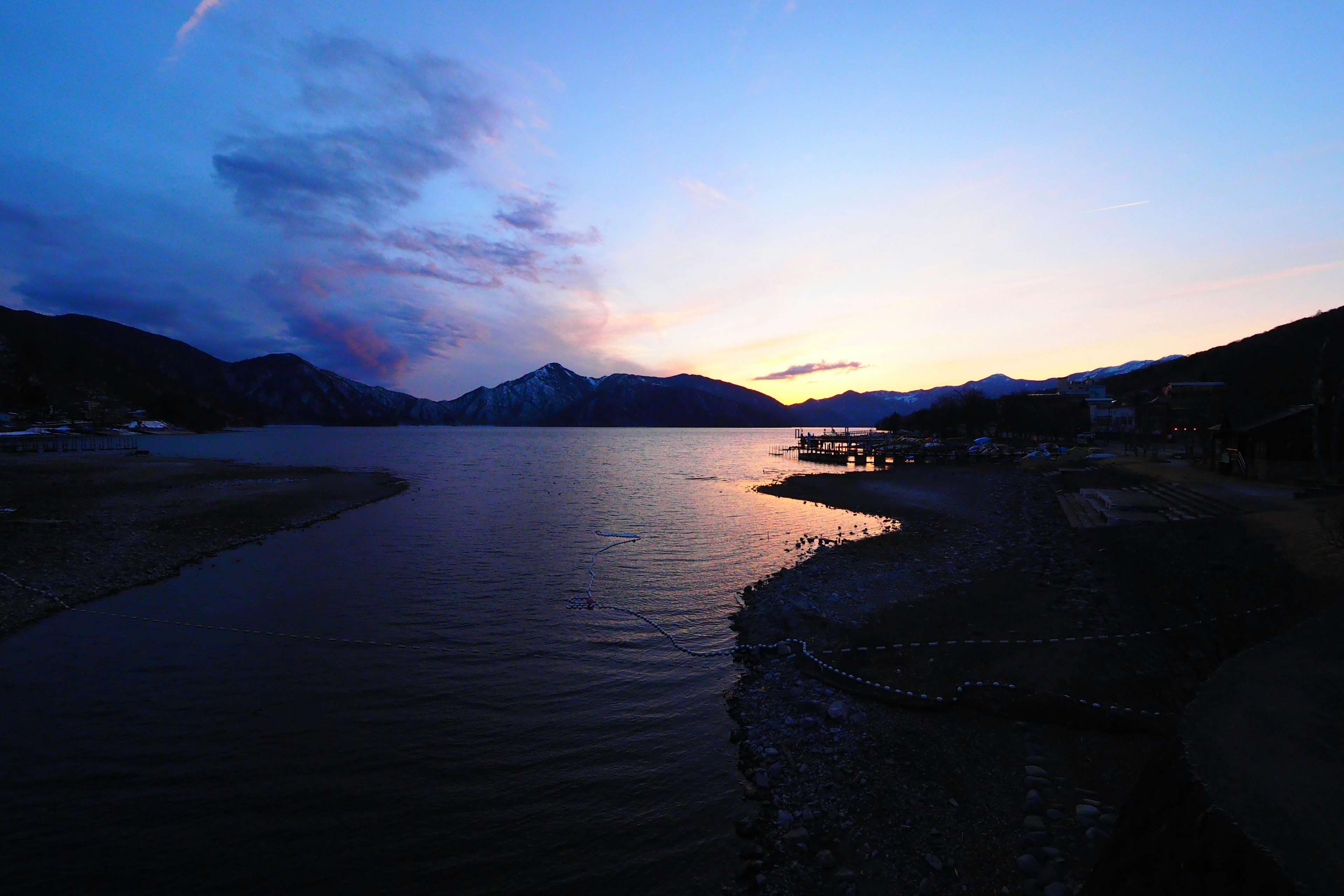 Ruhige Seenlandschaft bei Sonnenuntergang umgeben von Bergen