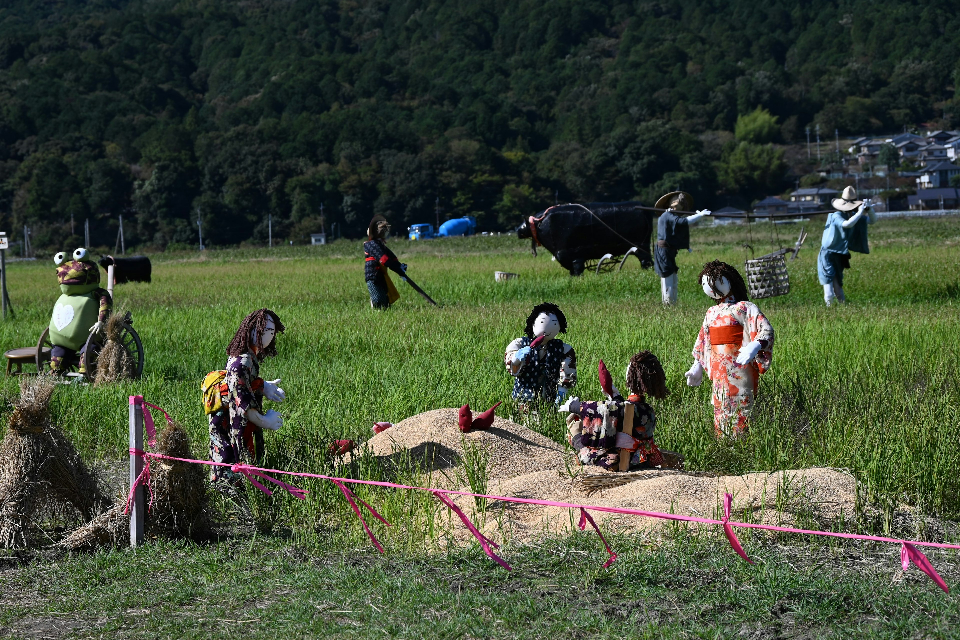 Scene of scarecrows and people working in a rice field