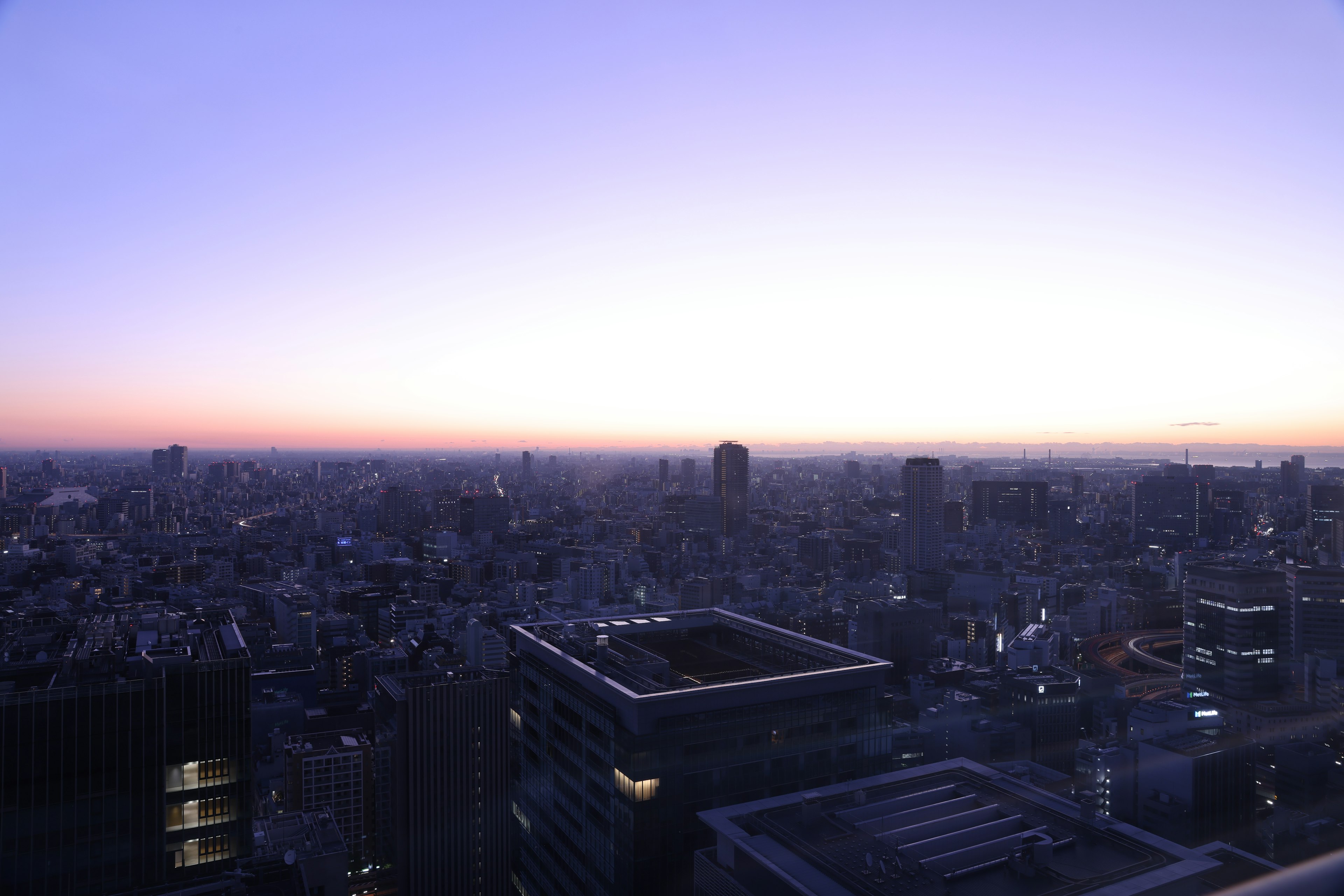 Vista panorámica de una ciudad al anochecer con rascacielos y un cielo brillante