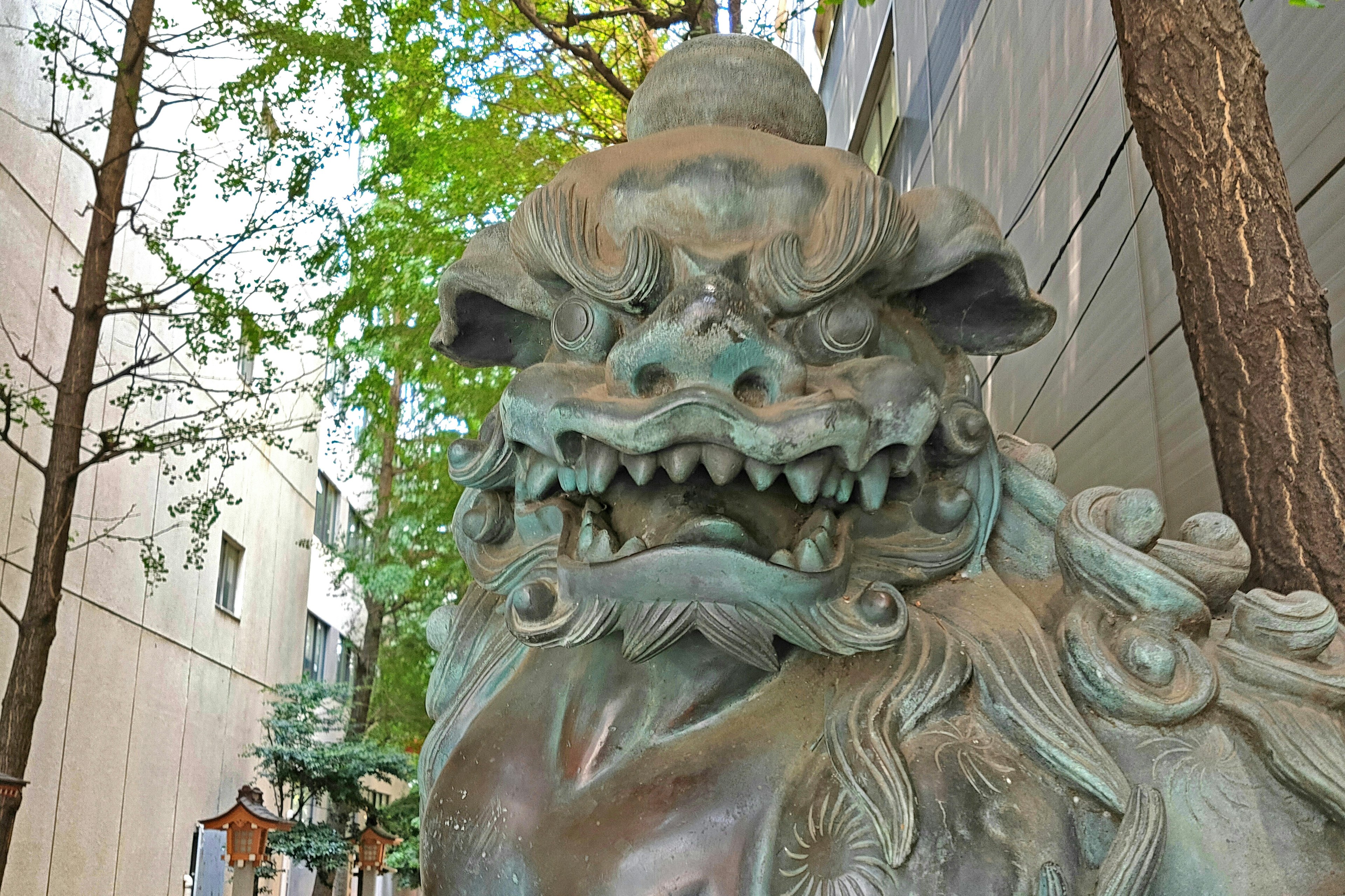 Sculpture de lion située dans un environnement urbain expression féroce dents acérées entourée de verdure