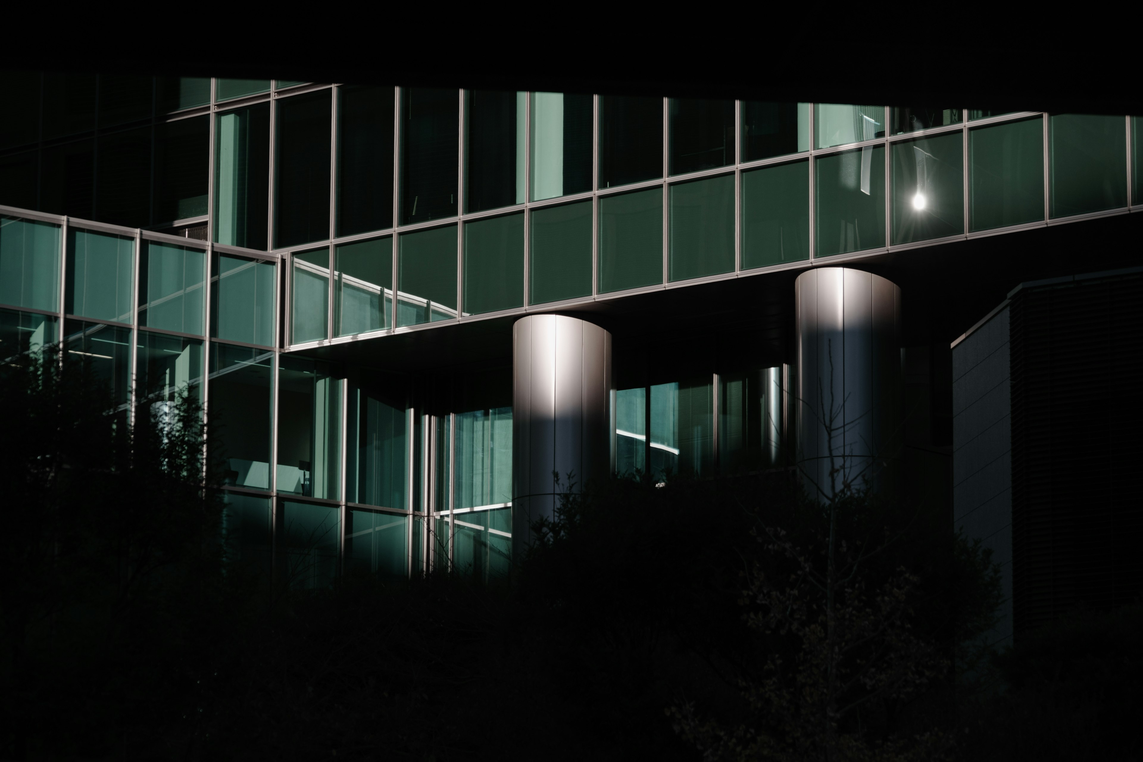 Part of a glass building illuminated at night with lit columns