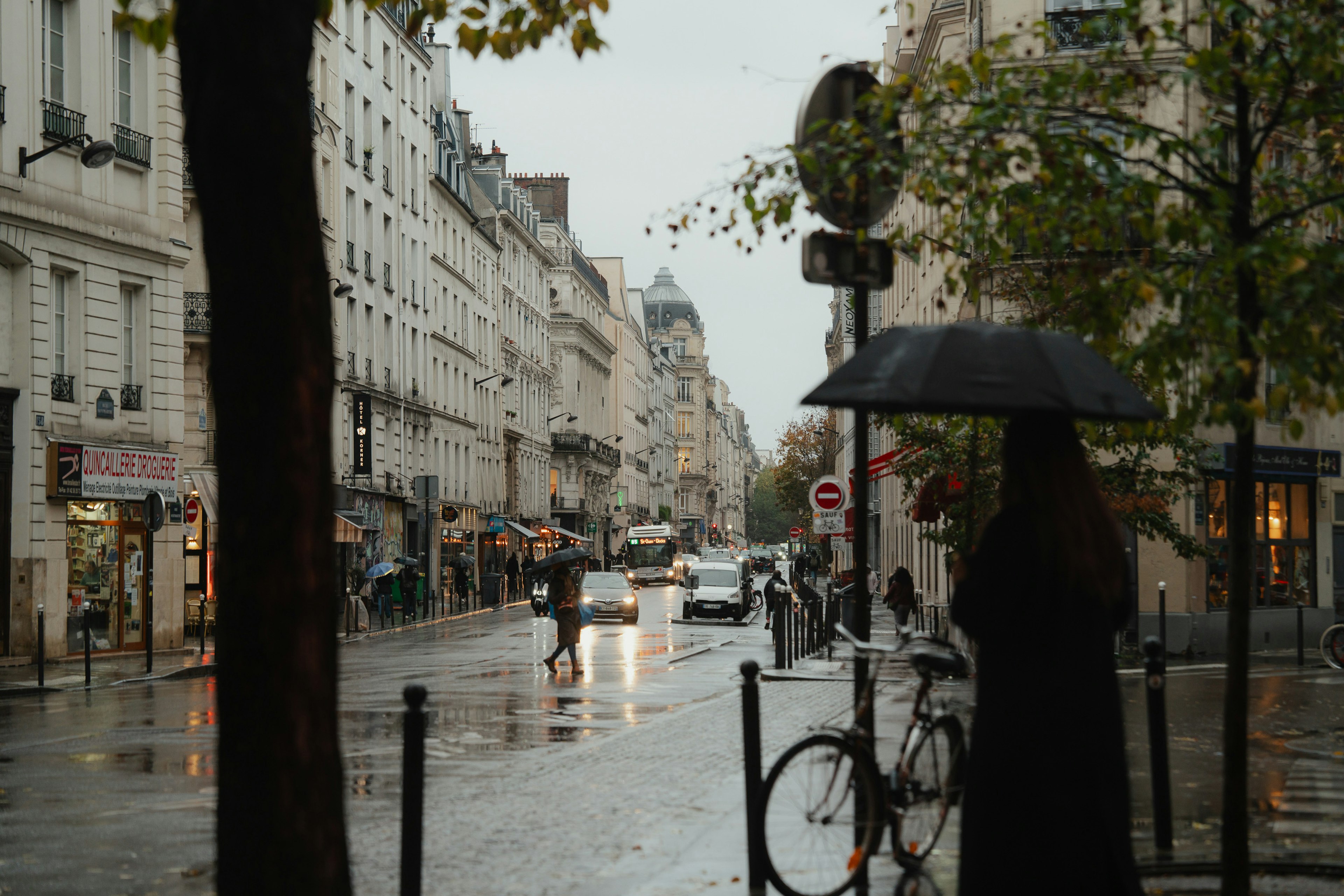 Rainy Paris street scene with a person holding an umbrella and a bicycle