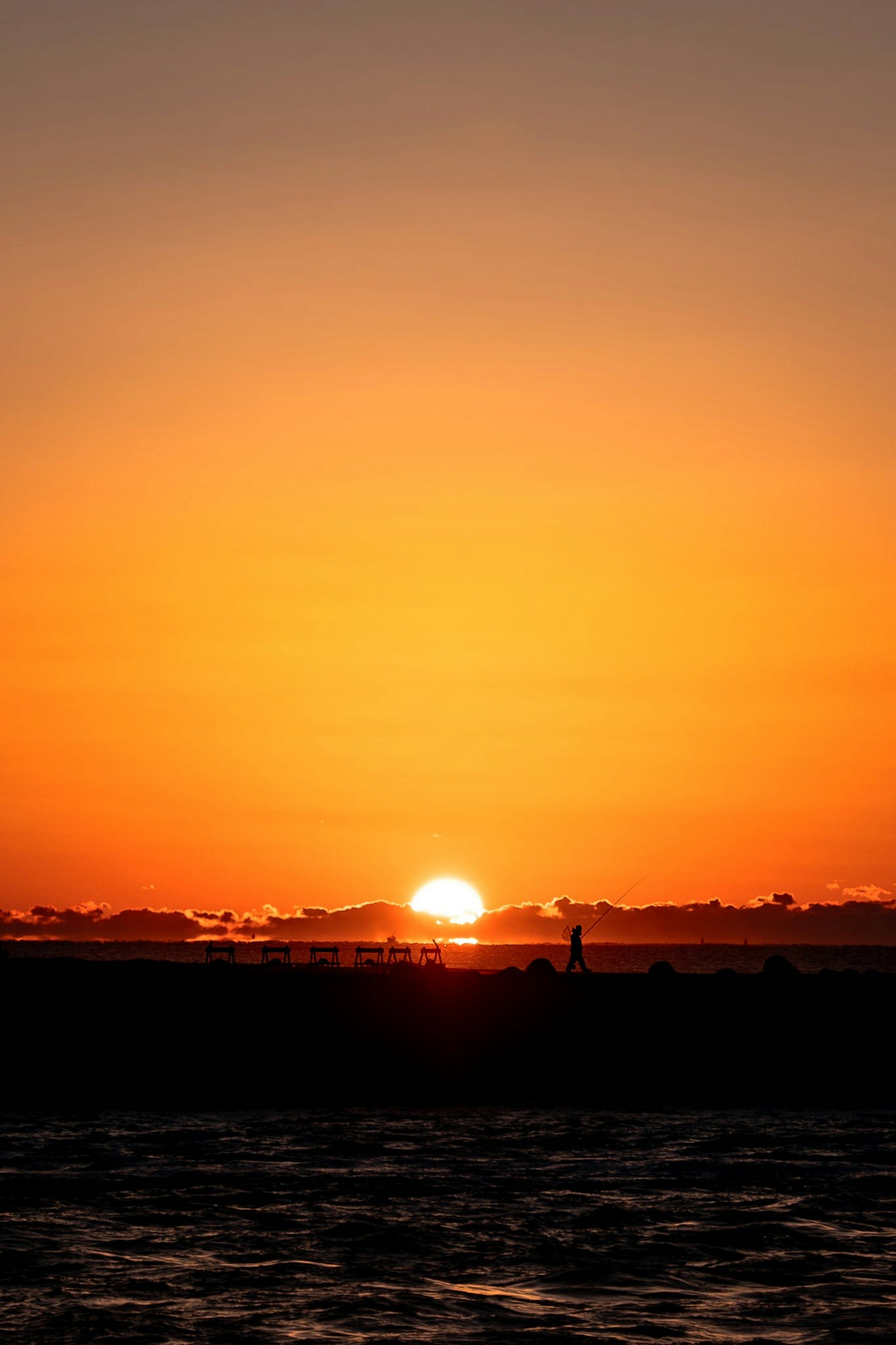 オレンジ色の夕焼けの中で沈む太陽と静かな海