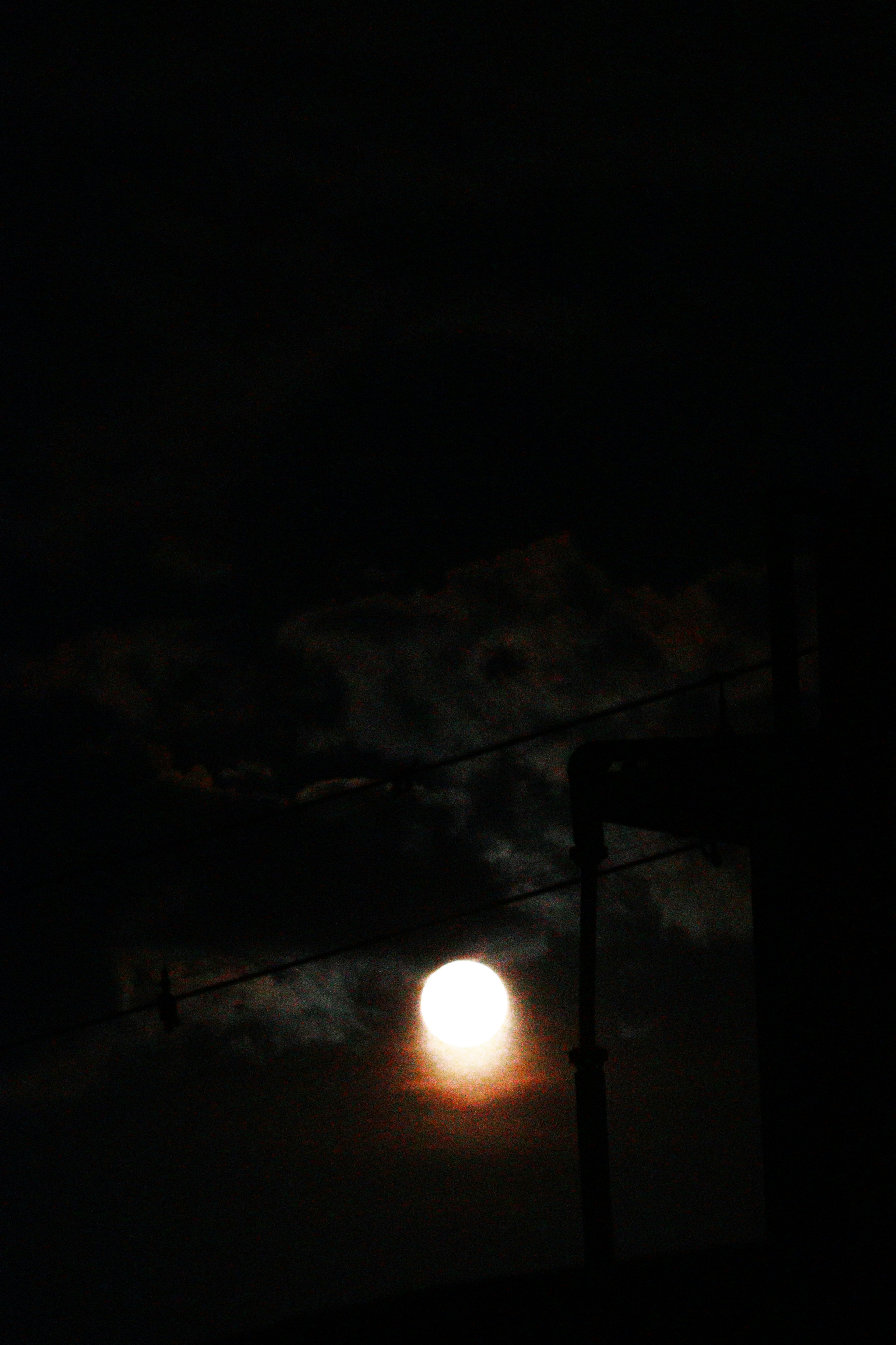 Bright moon surrounded by clouds in the night sky