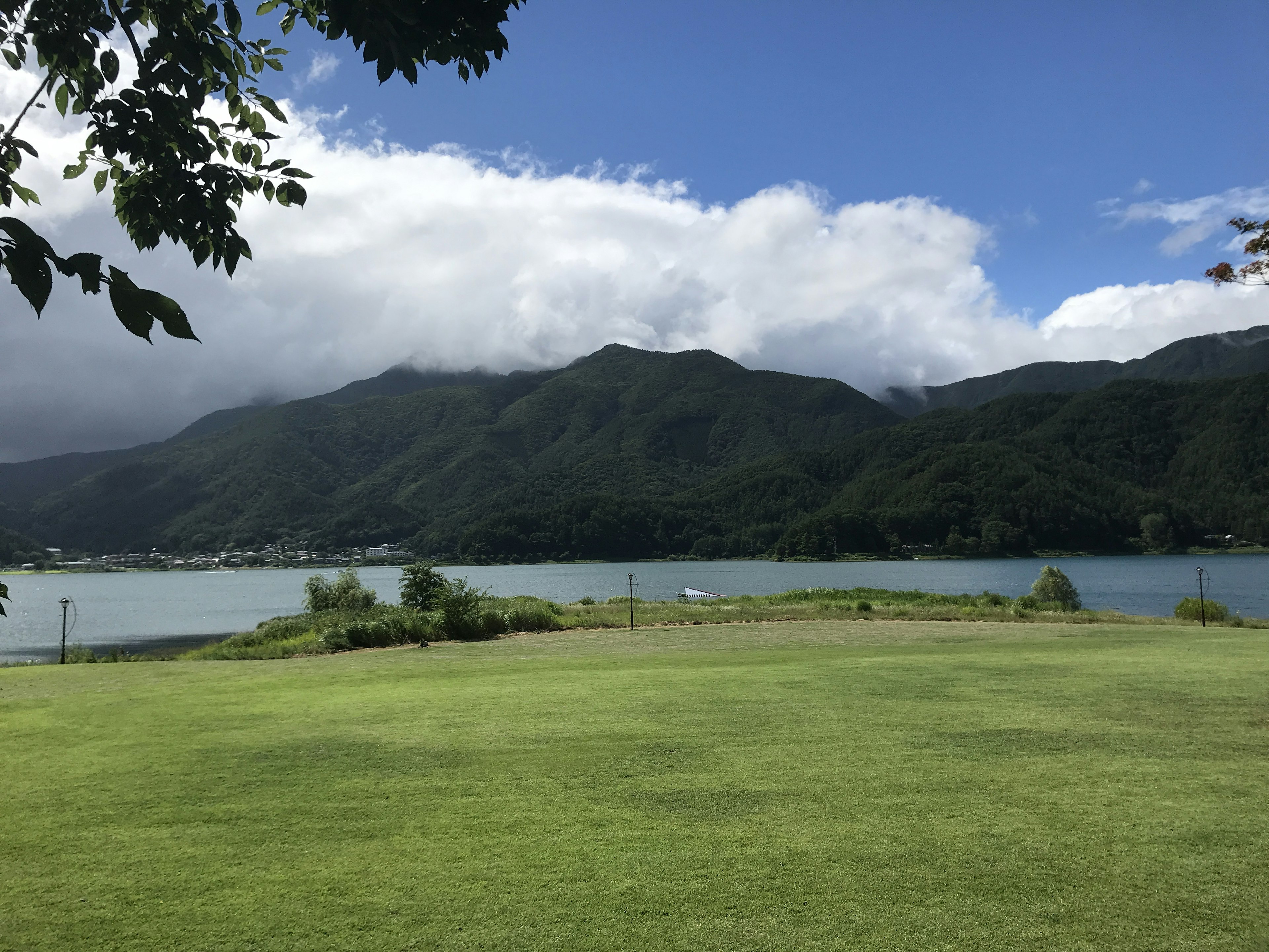 Hermoso paisaje de un lago y montañas con césped verde y cielo azul