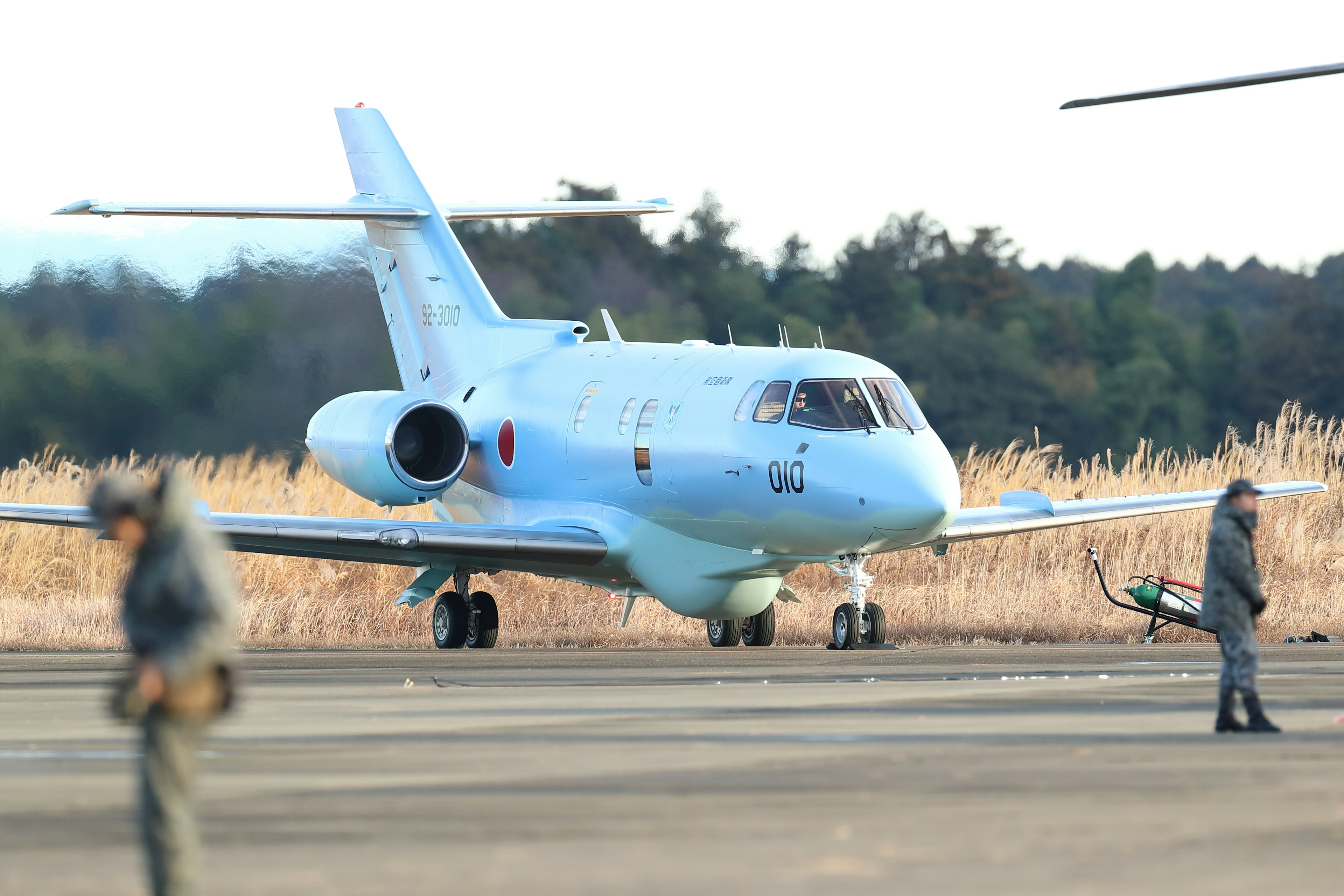 Avion bleu sur la piste avec du personnel en uniforme