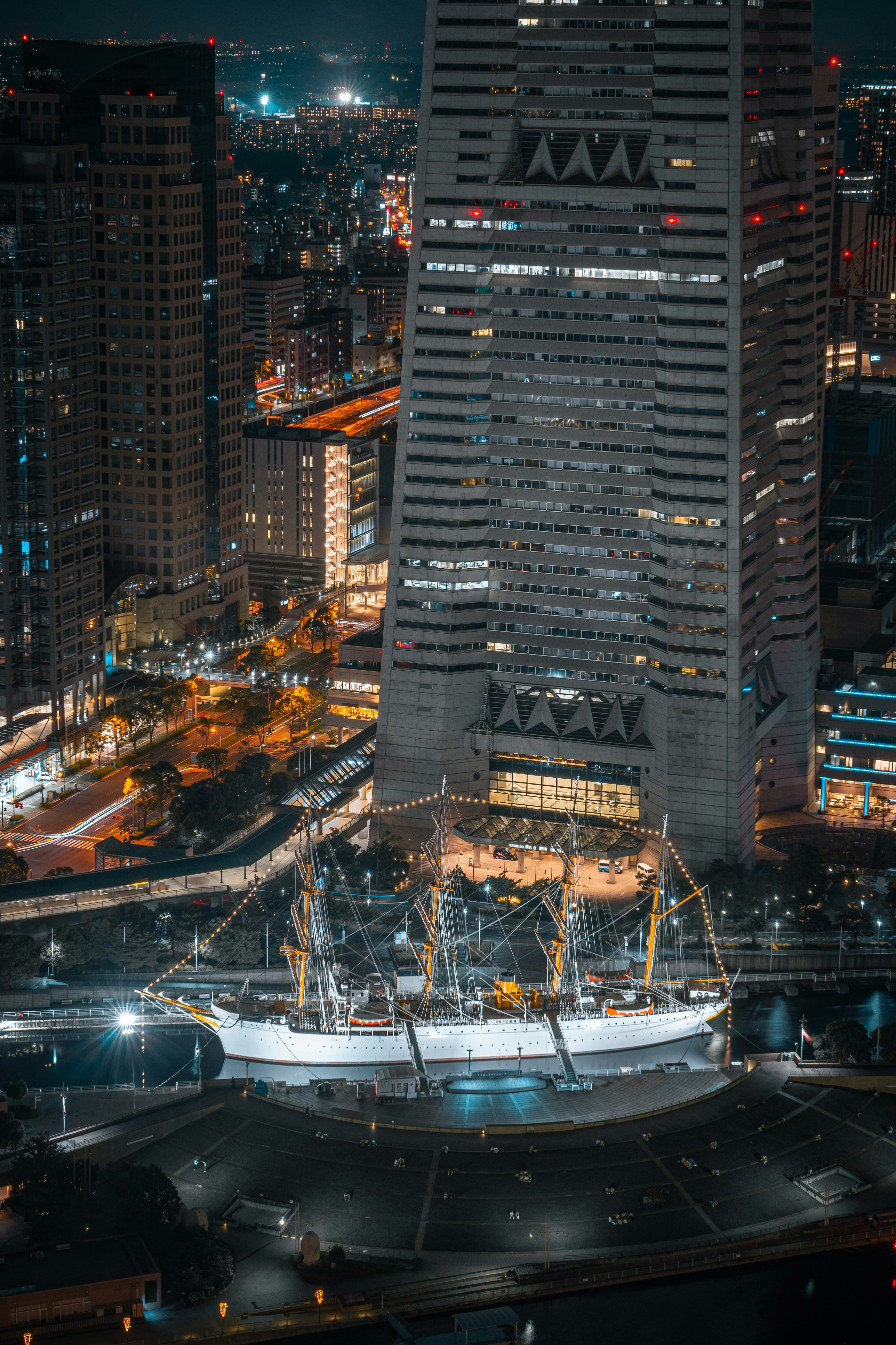 Night view of a large sailing ship in front of a skyscraper