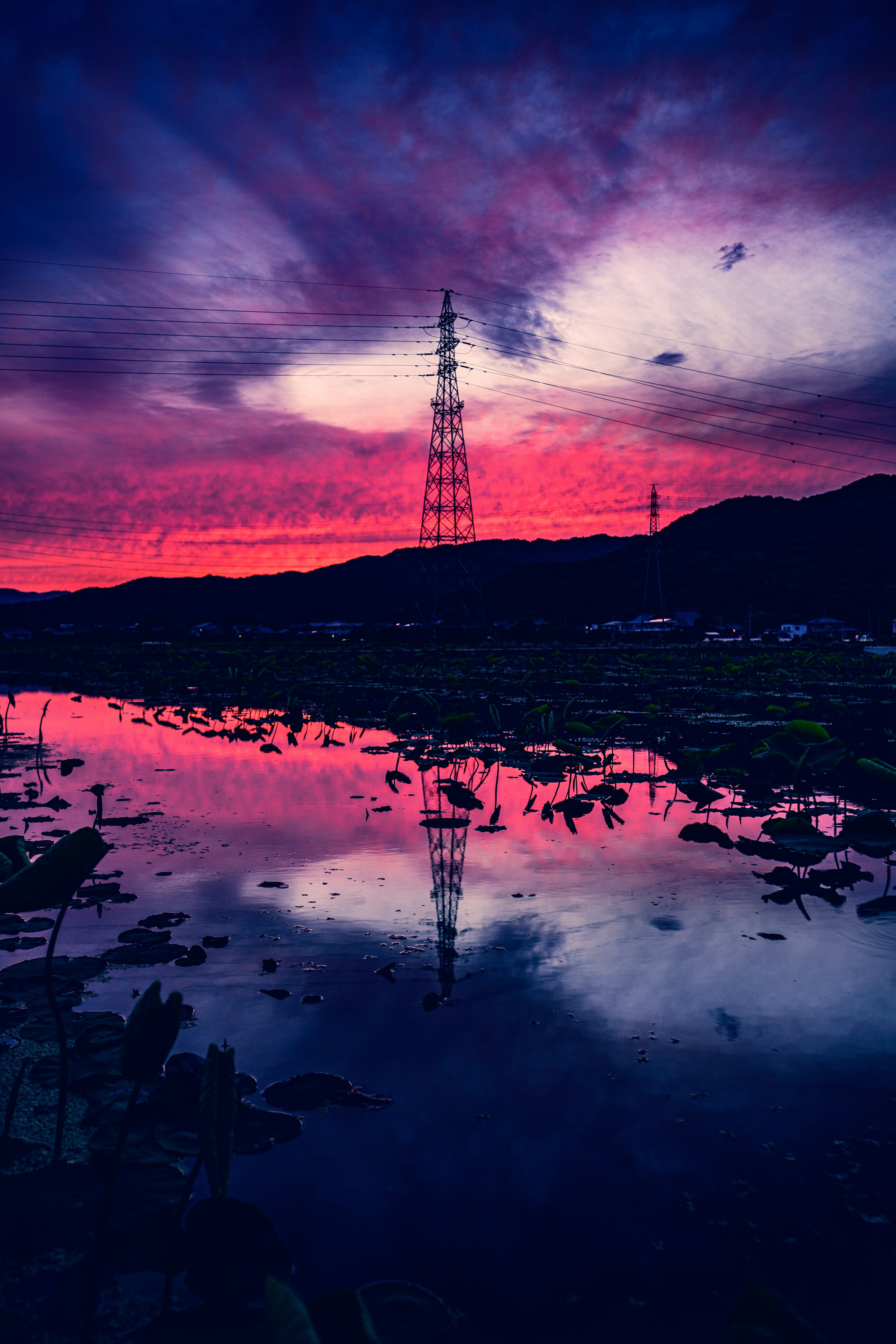 Ciel de coucher de soleil magnifique avec reflet d'une tour électrique dans l'eau