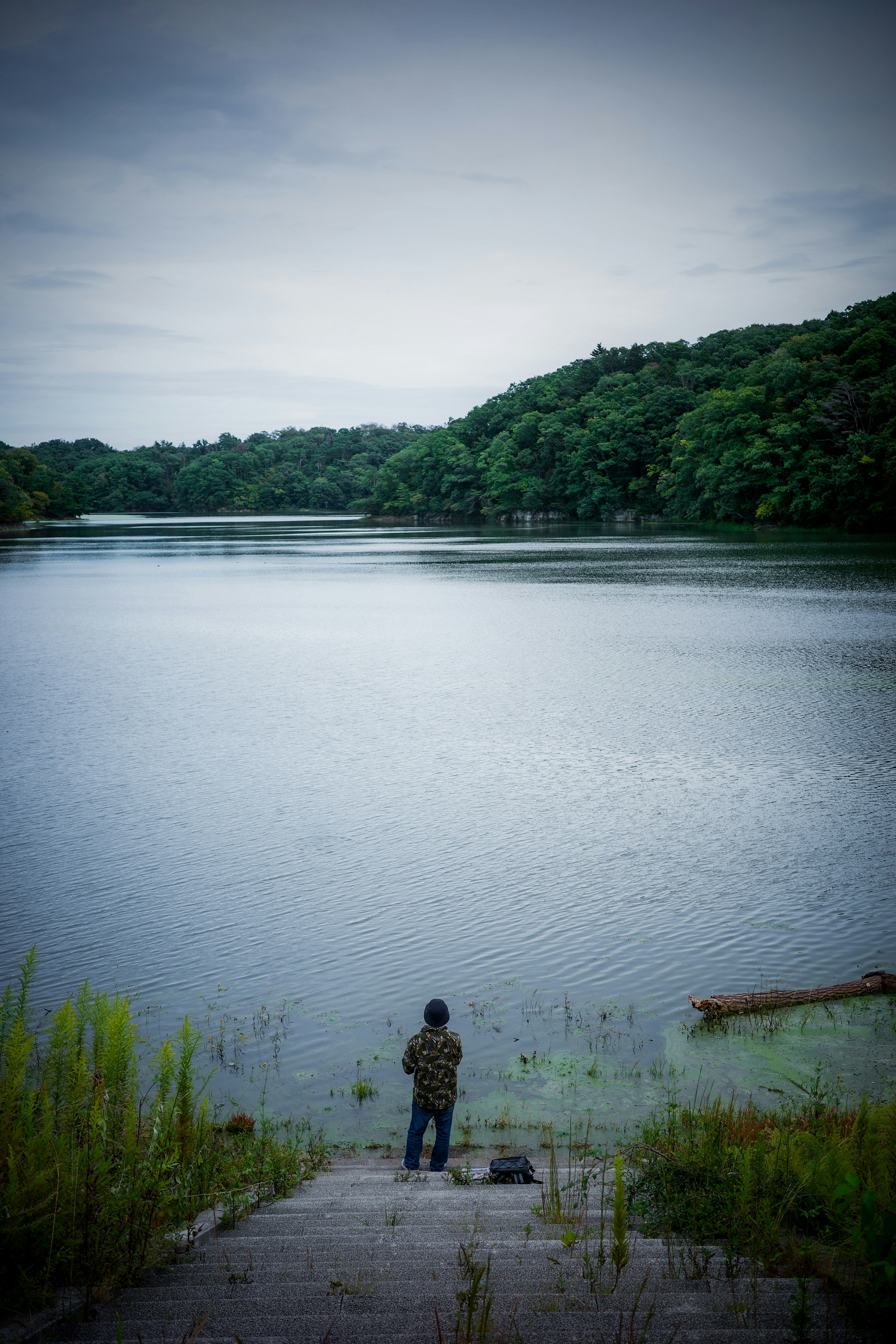 少年が湖のほとりで静かに立っている風景