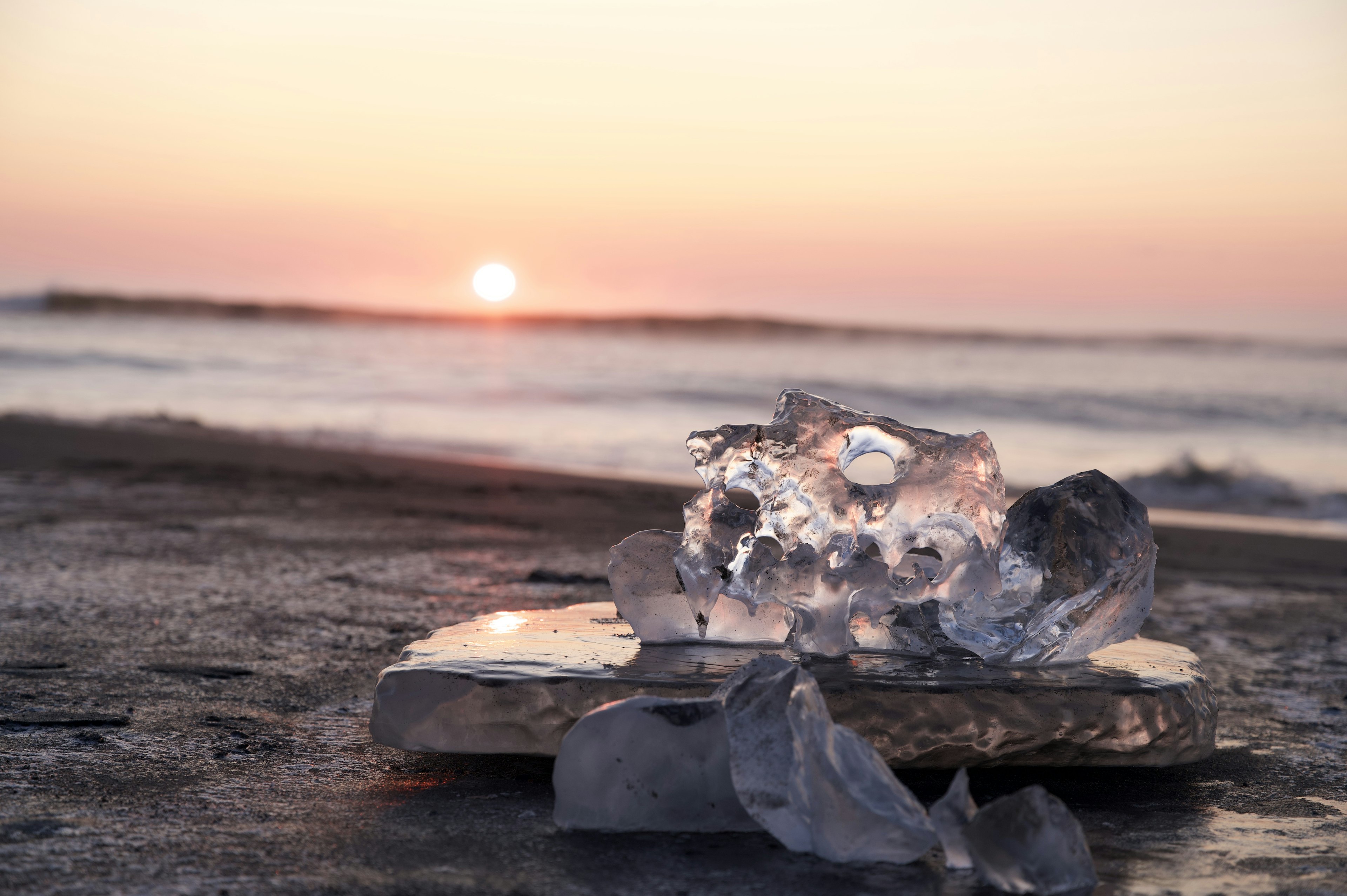 Trozos de hielo en una playa con un atardecer de fondo