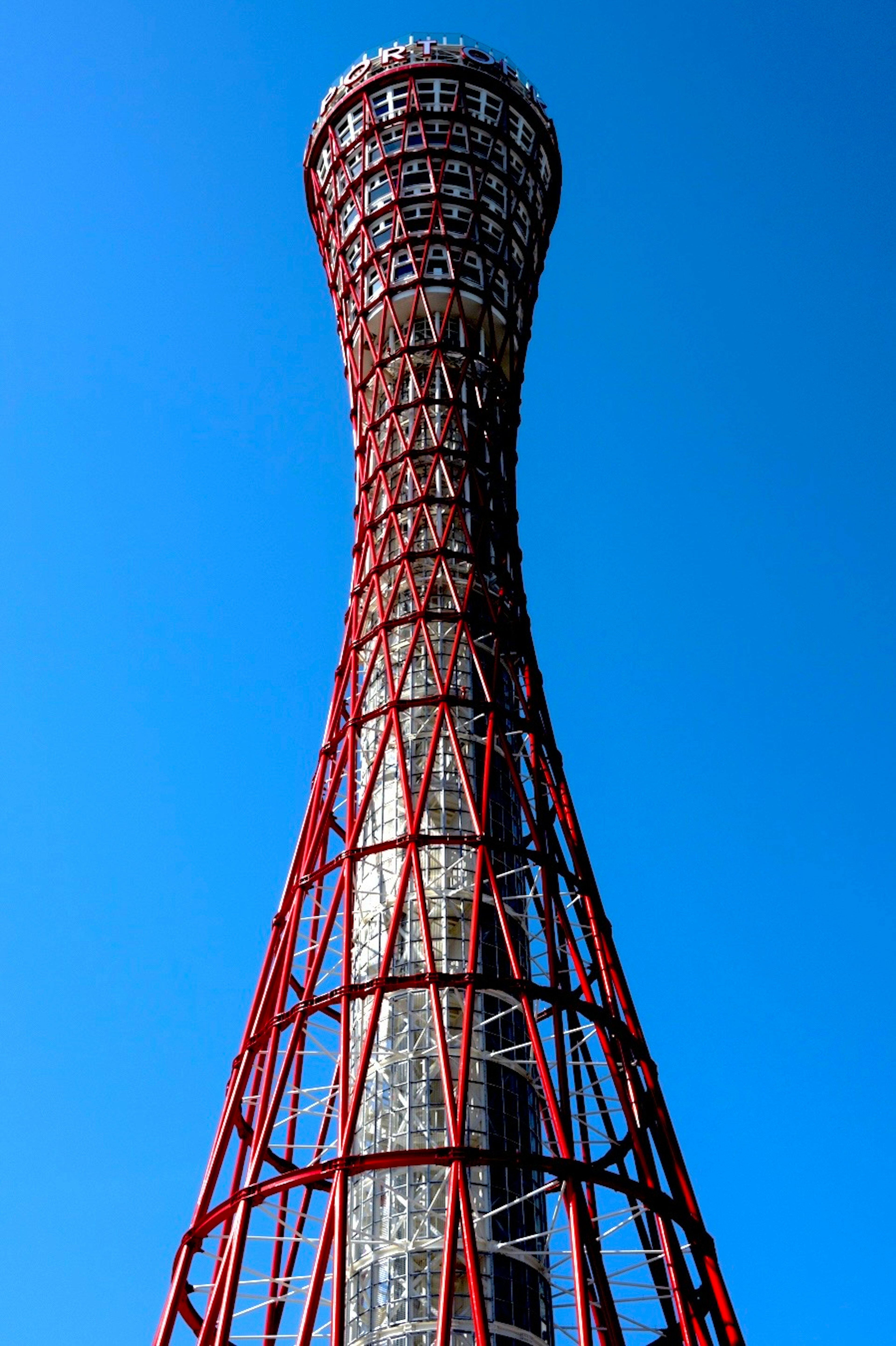 Kobe Port Tower mit markanter roter Stahlstruktur vor blauem Himmel