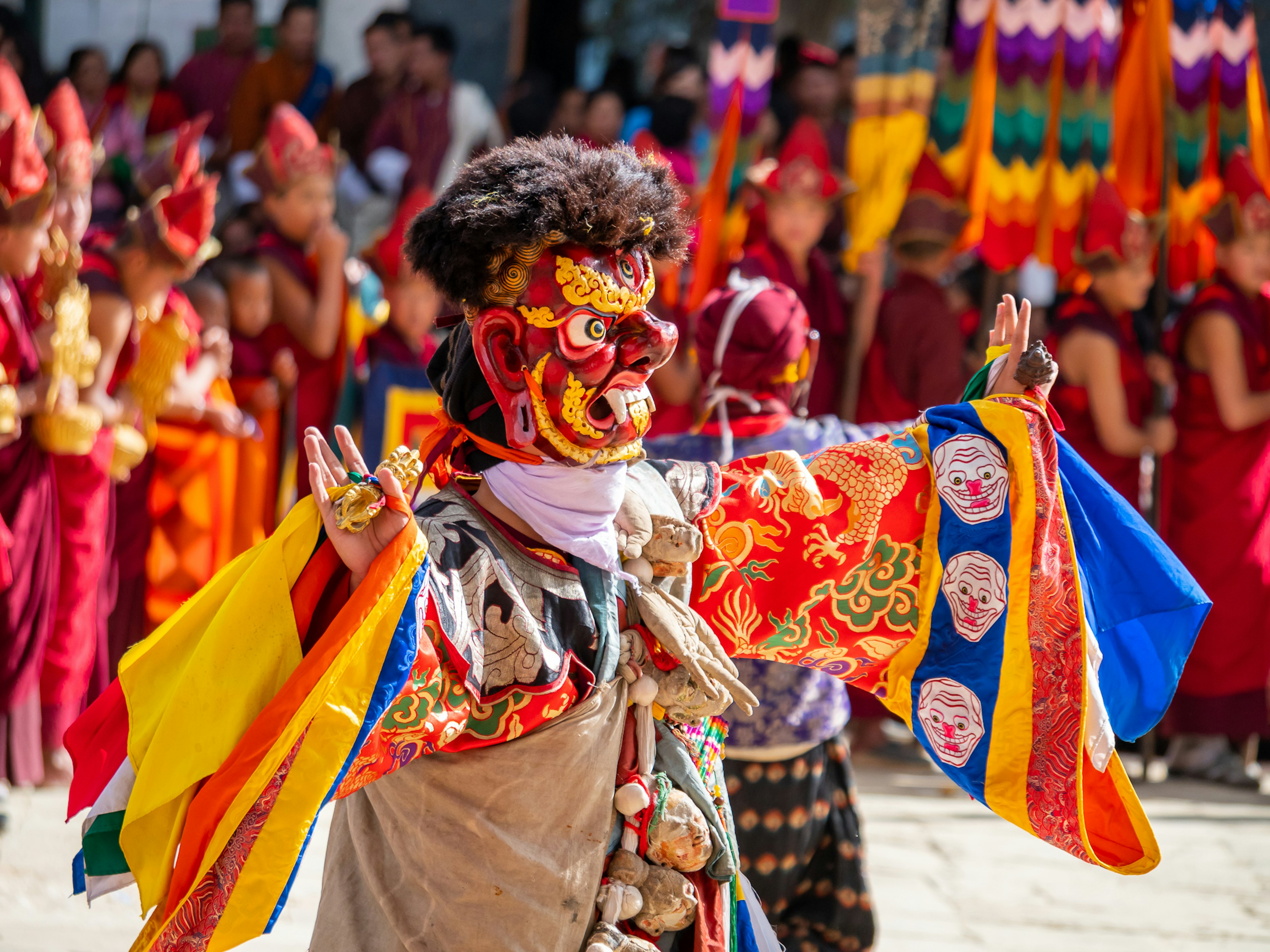 Dancer in vibrant costume performing at festival with crowd in background