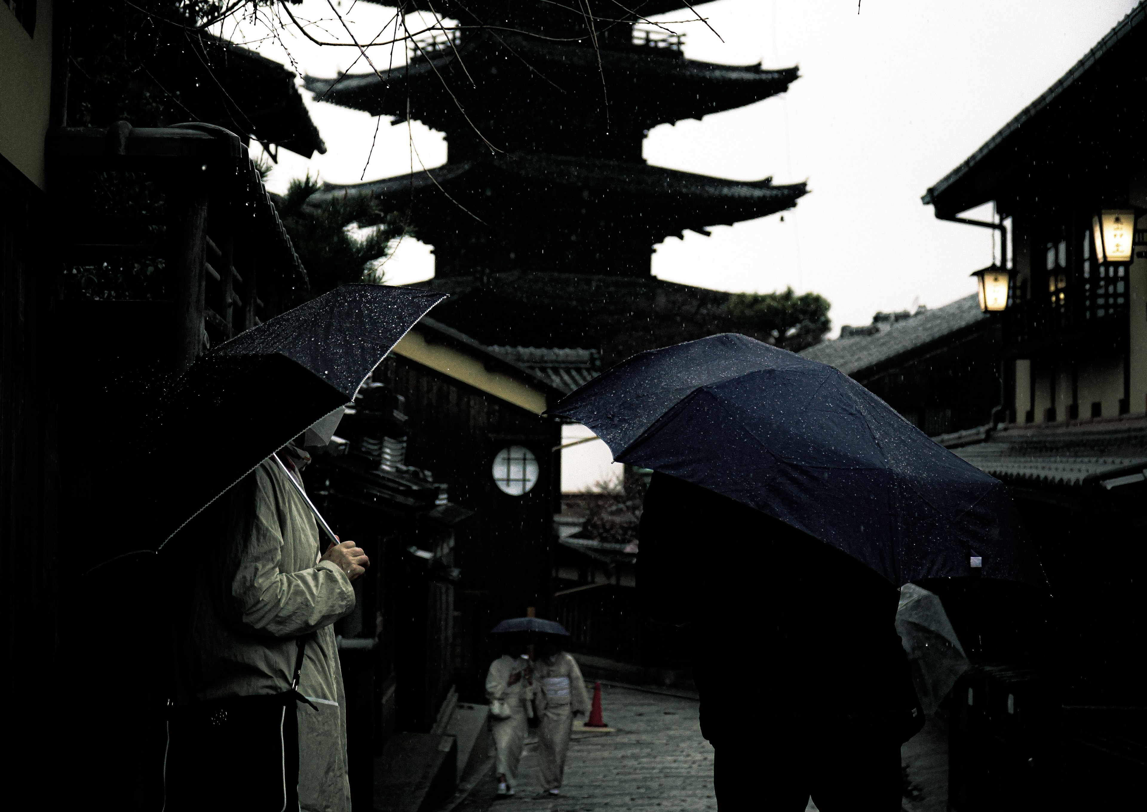 雨の中で傘を持つ人々と古い建物が見える風景