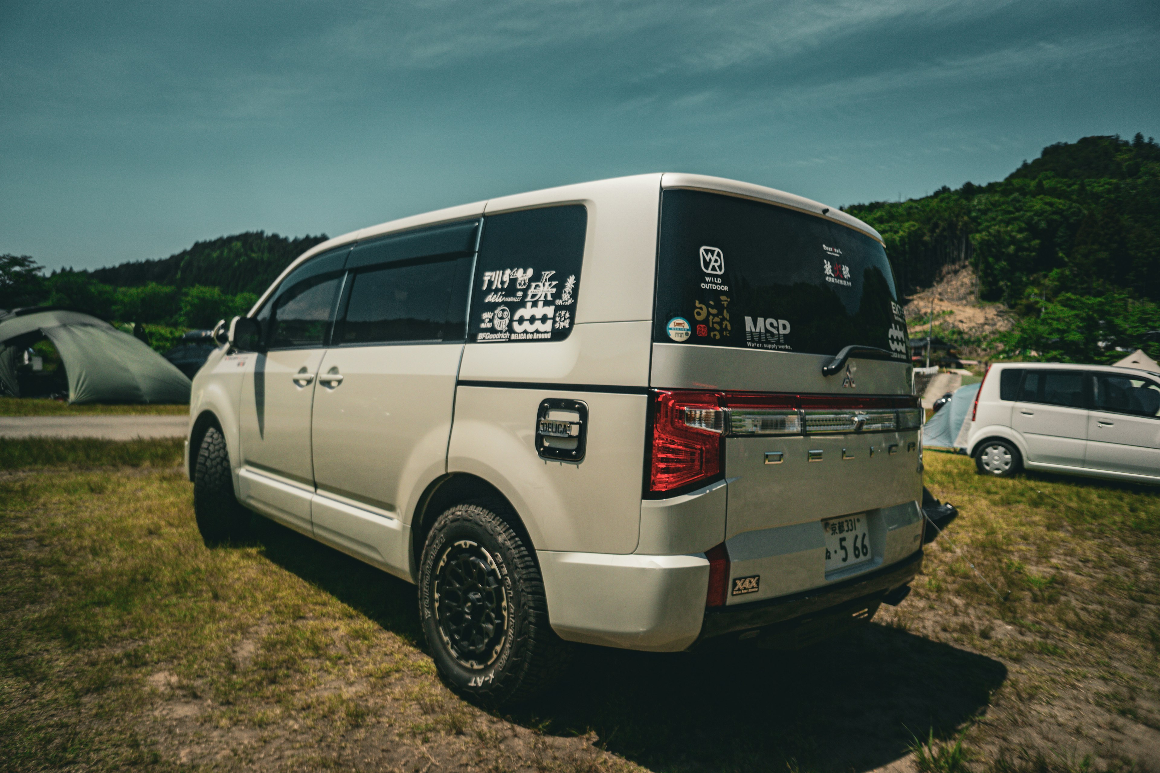 Fourgonnette blanche garée dans un camping avec des autocollants visibles