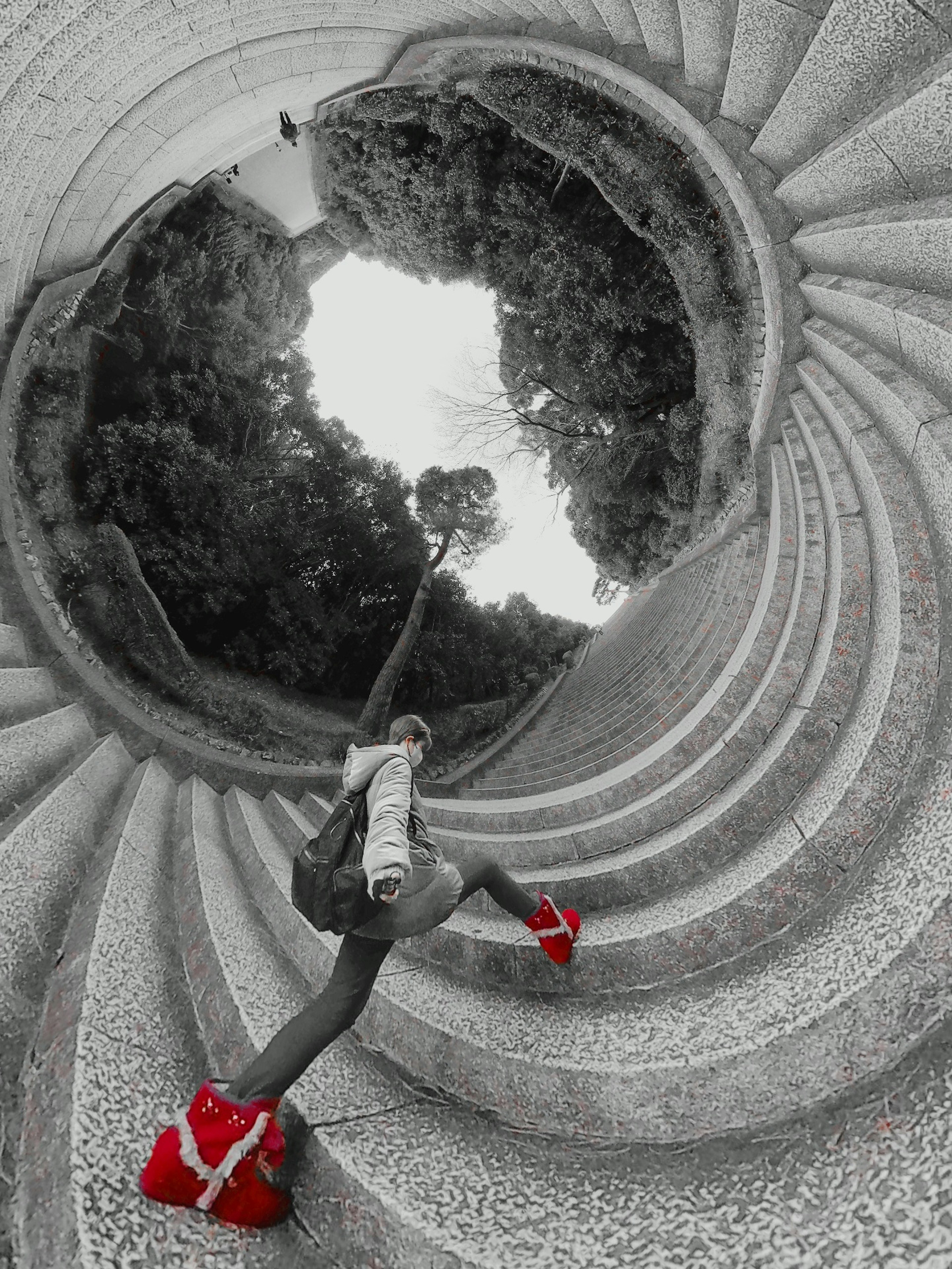 Une femme grimpant un escalier en spirale avec des chaussures rouges et un fond monochrome