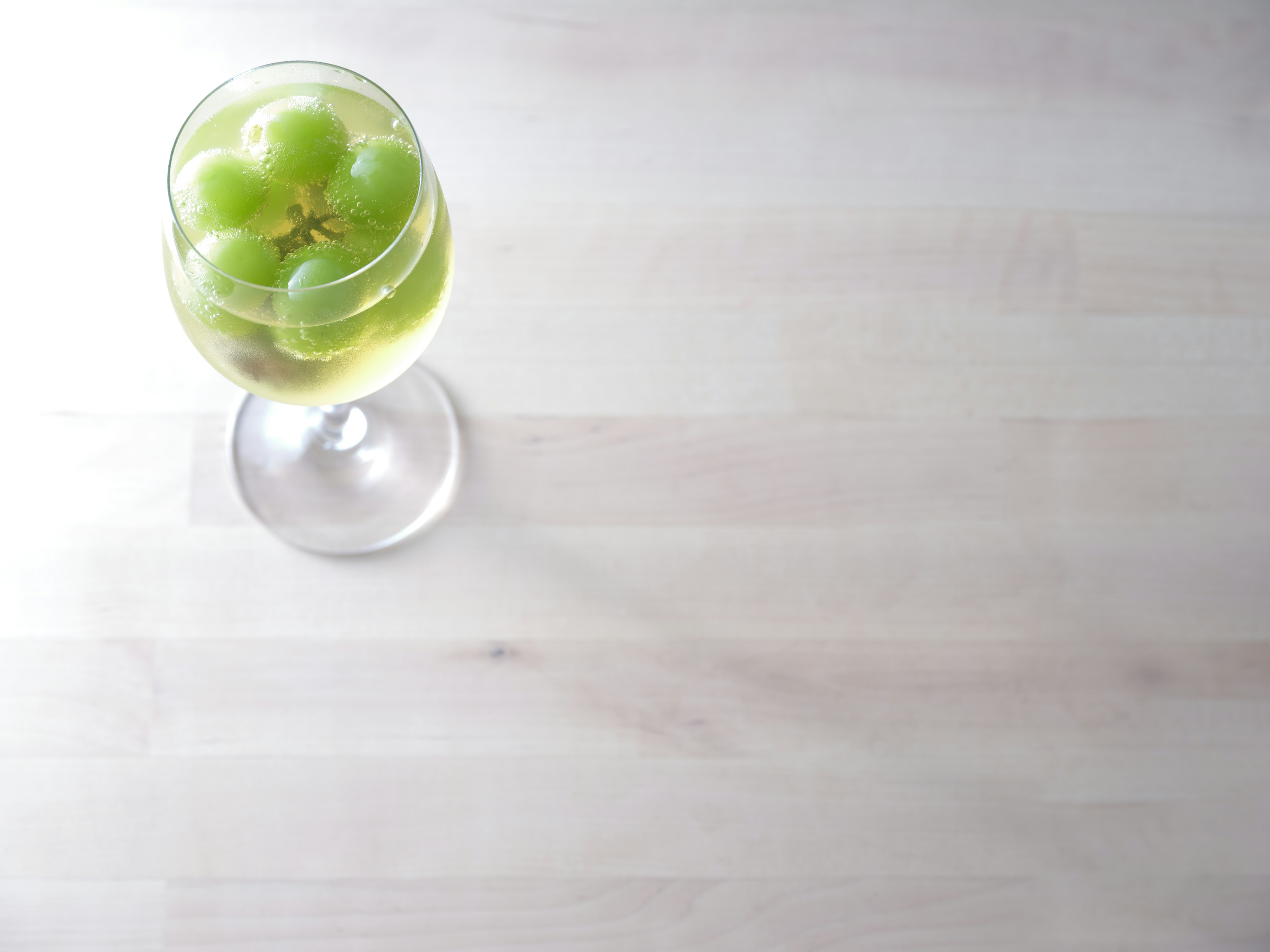 Un verre transparent rempli de raisins verts et de liquide