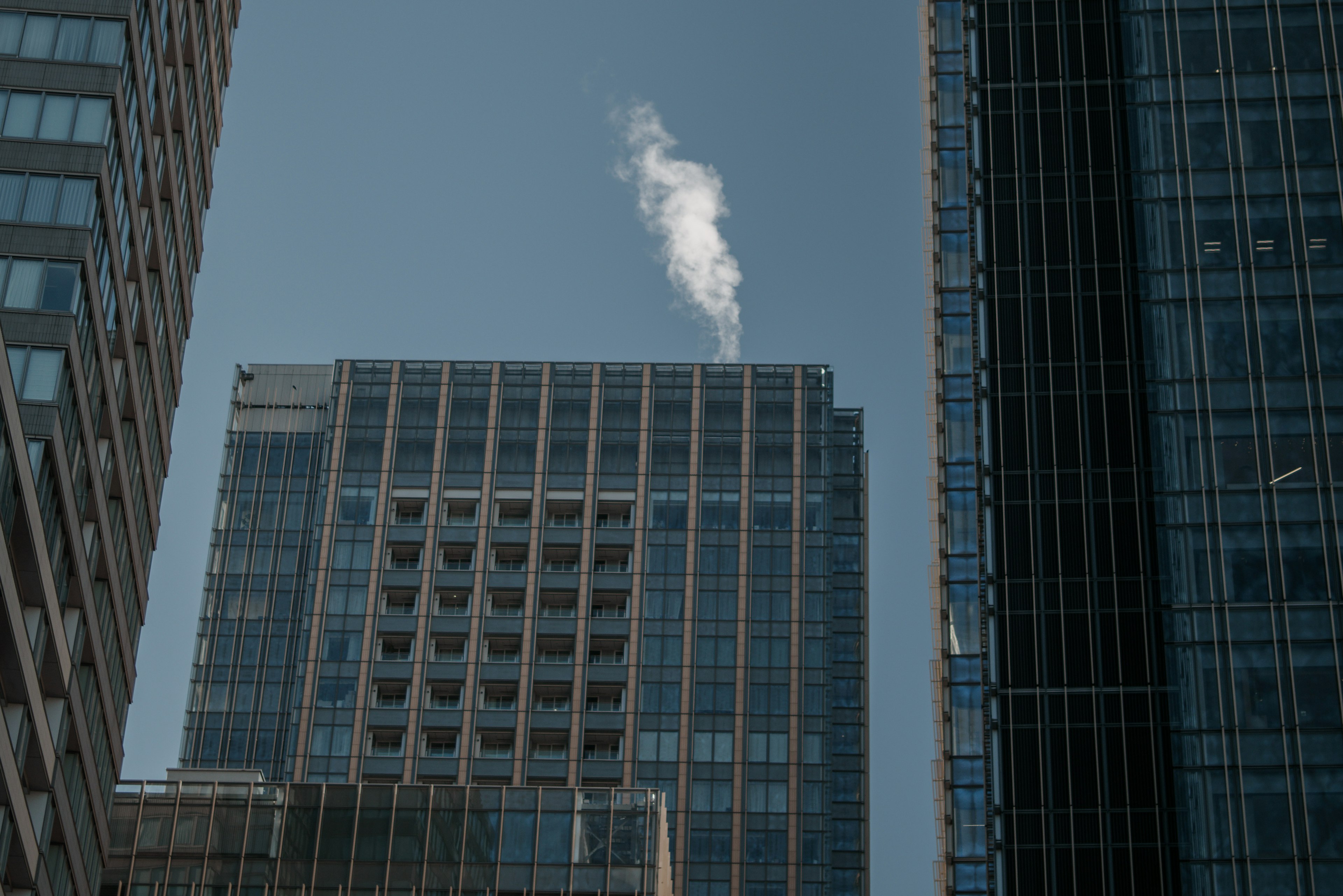 Edificio que emite humo visto entre altos rascacielos